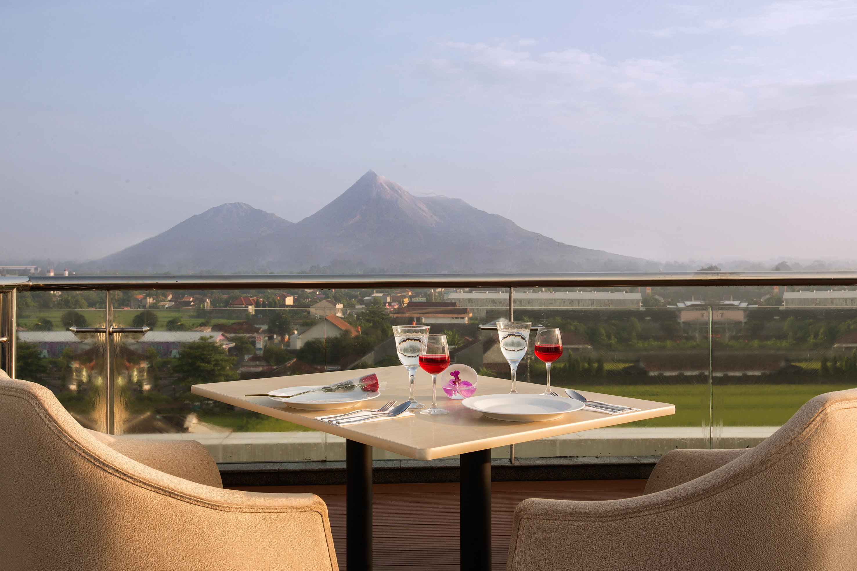 Rooftop dining table for two with wine, rose, and distant mountain view.