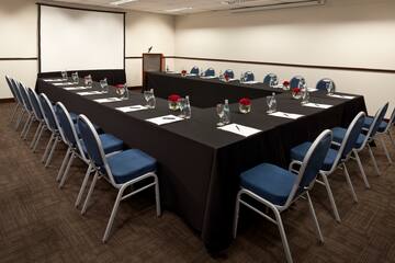 a long conference room with black tablecloths and blue chairs