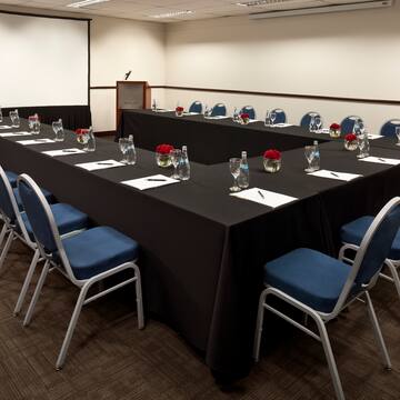 a long conference room with black tablecloths and blue chairs