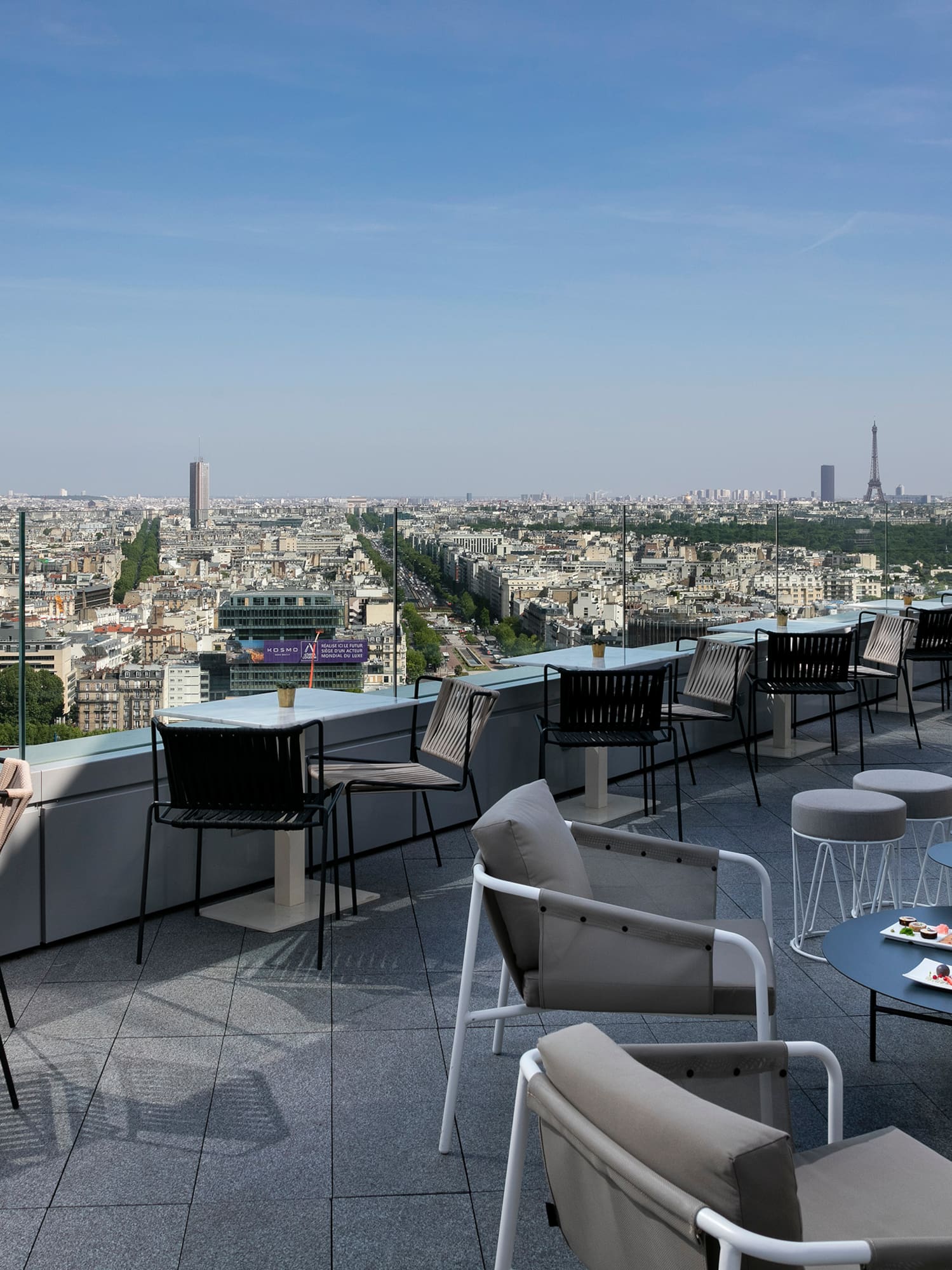 a rooftop patio with chairs and tables and a city view