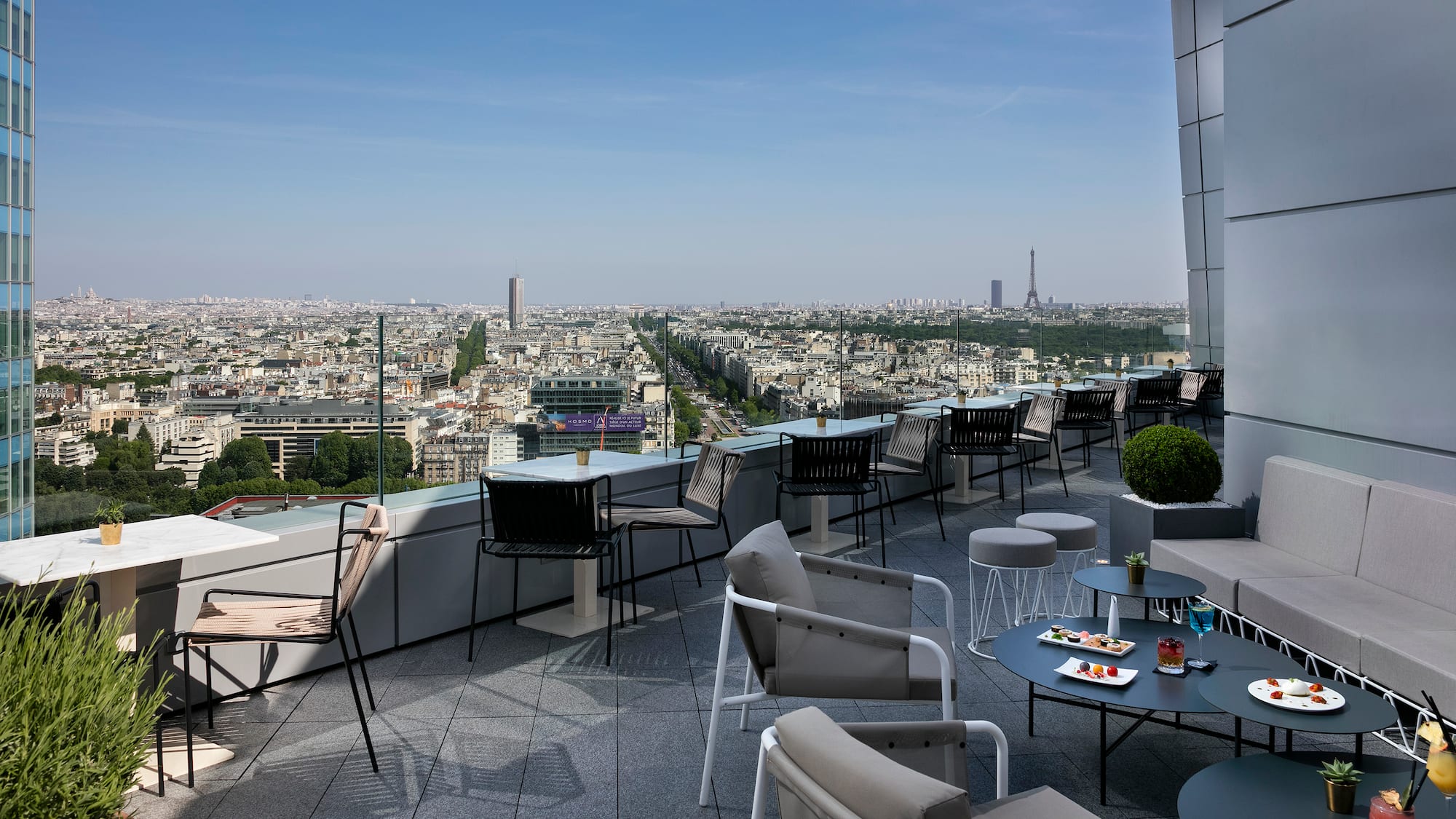 a rooftop patio with chairs and tables and a city view