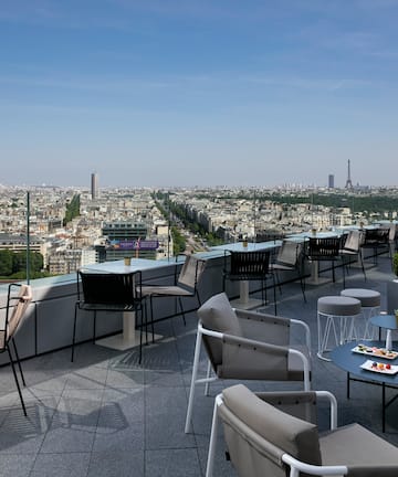 a rooftop patio with chairs and tables and a city view