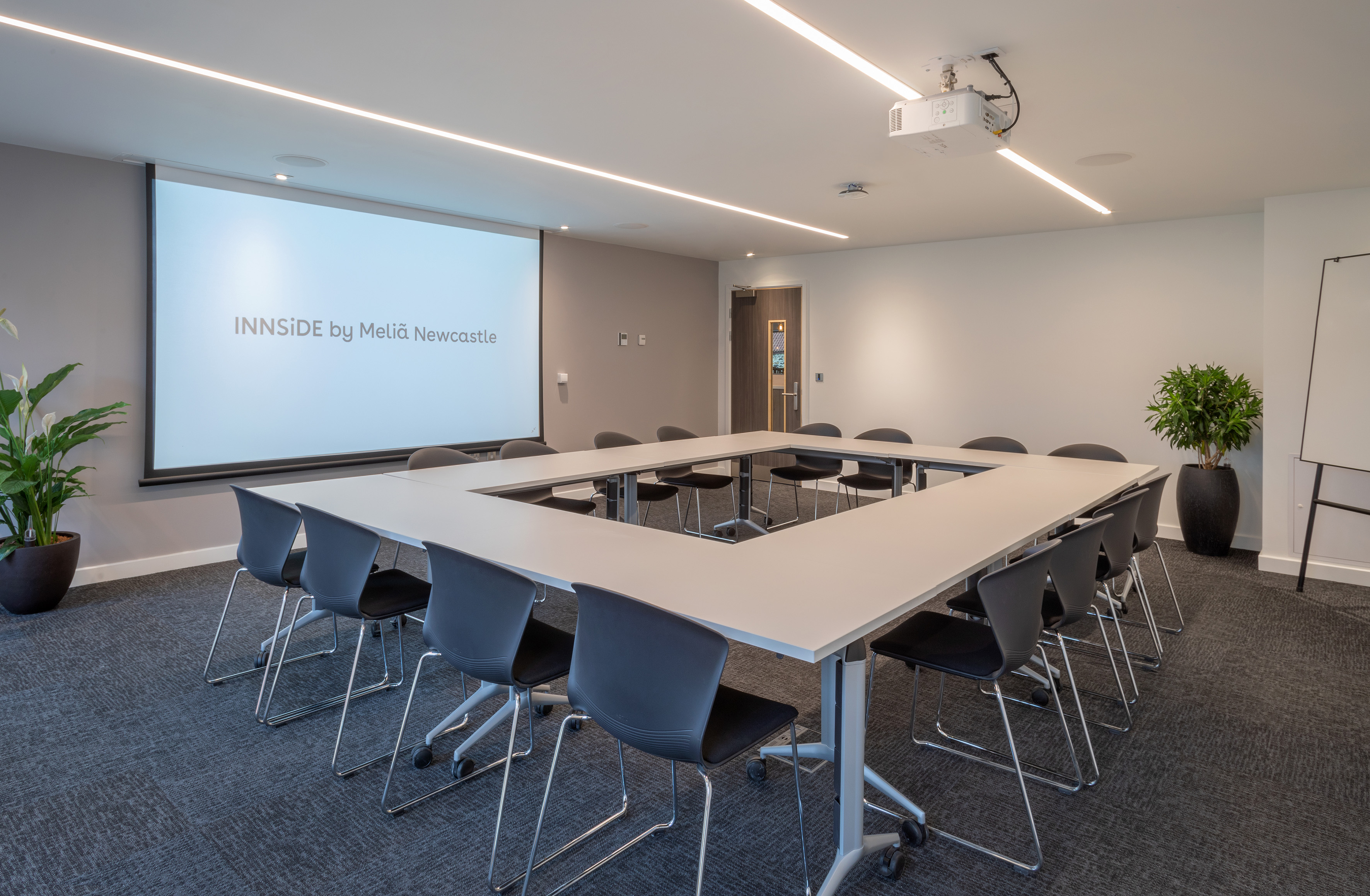 INNSiDE by Meliã Newcastle meeting room with projector screen, U-table setup.