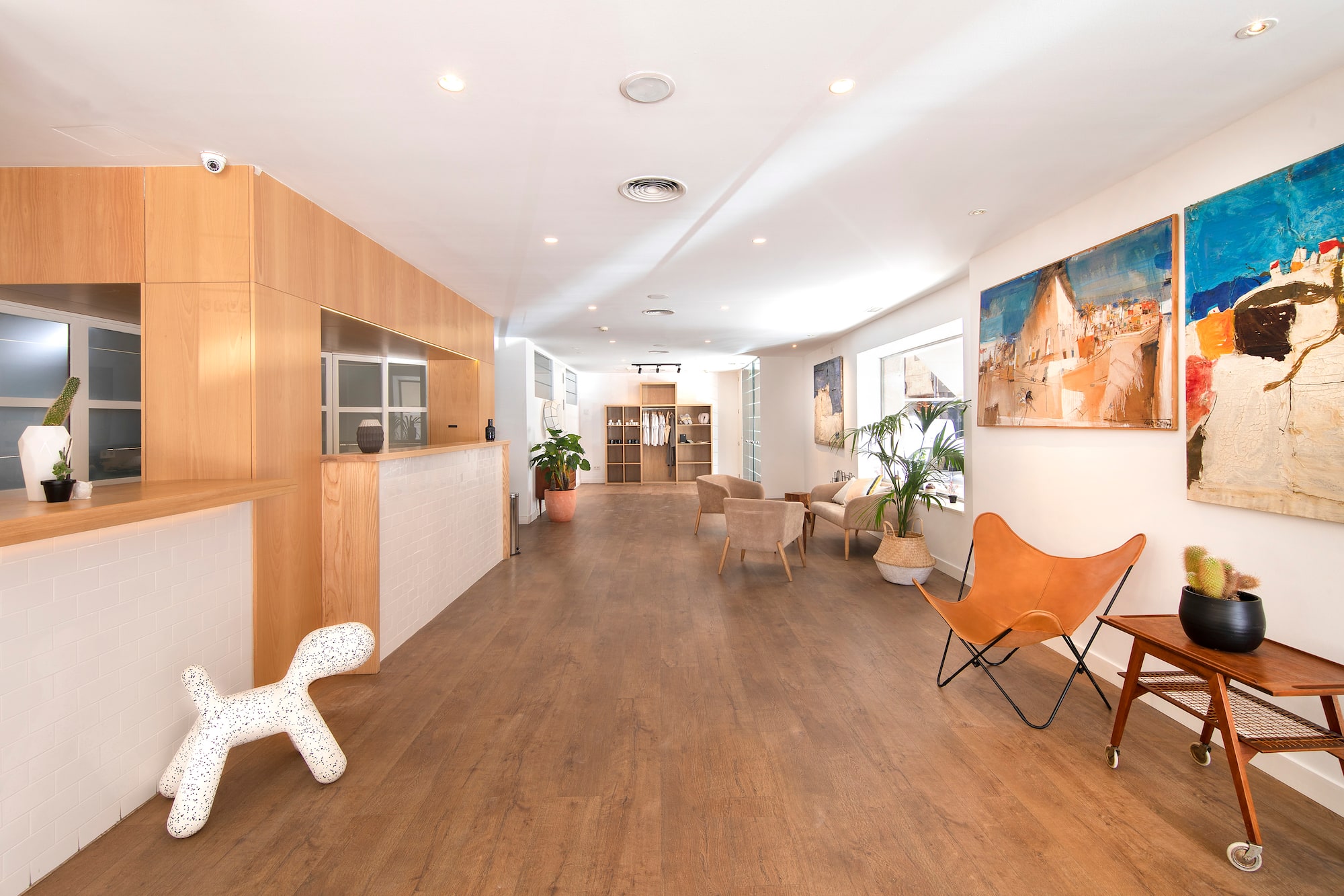 Bright modern showroom with wooden floor, reception, seating area, and wall art.