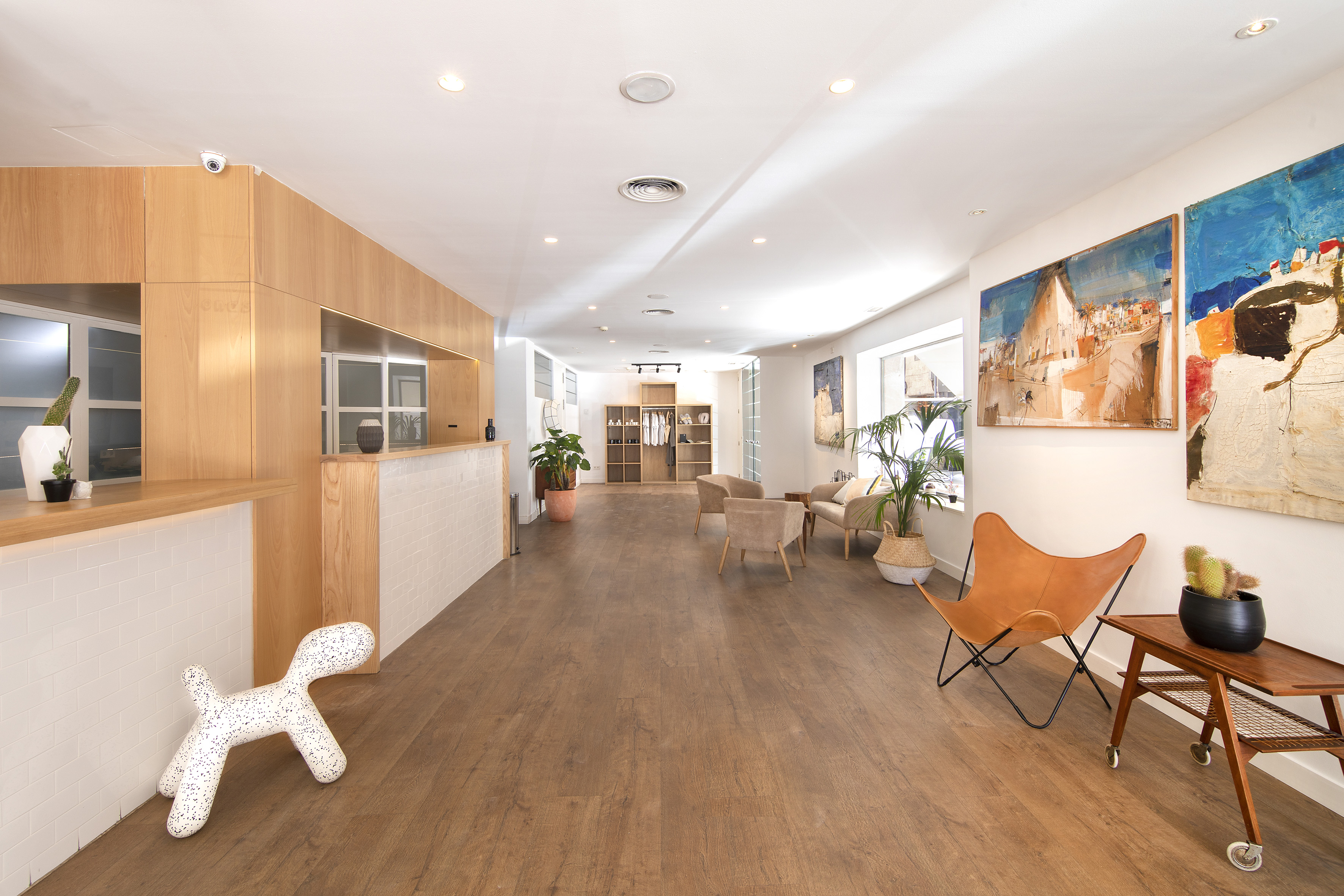 Bright modern showroom with wooden floor, reception, seating area, and wall art.