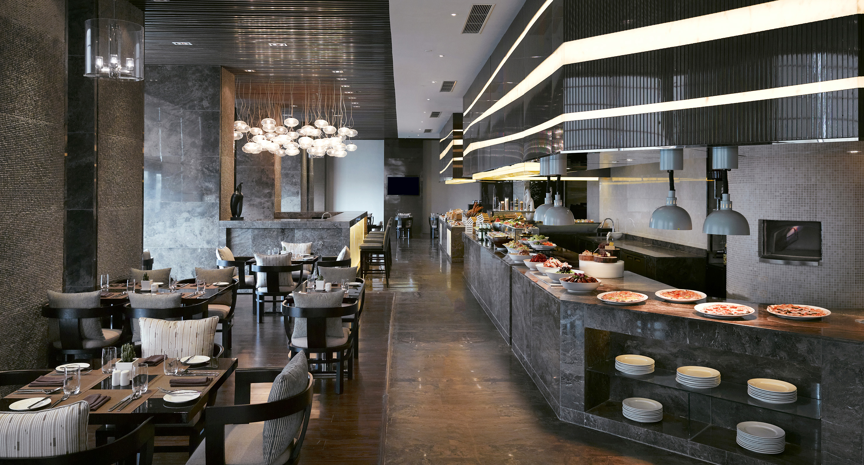 Modern upscale restaurant buffet with dining tables and diverse food display.