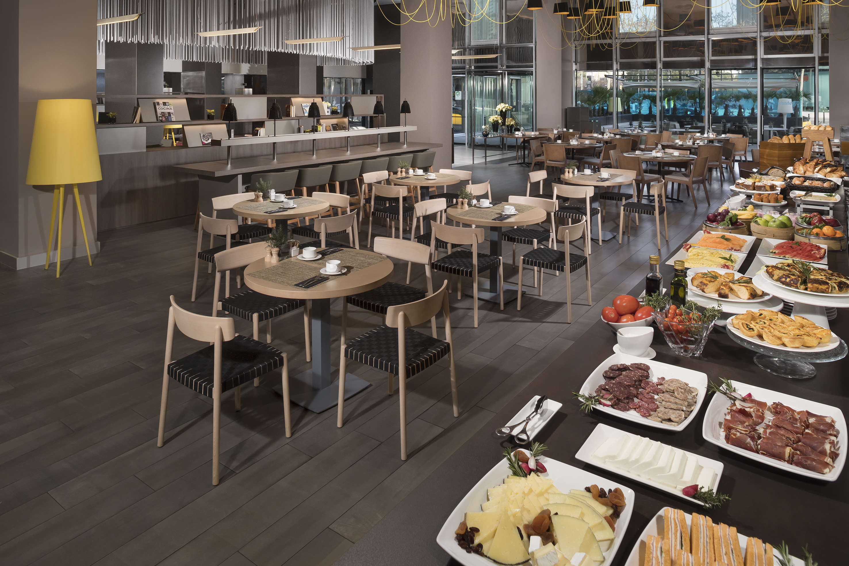 Modern hotel breakfast buffet with various dishes and dining tables.