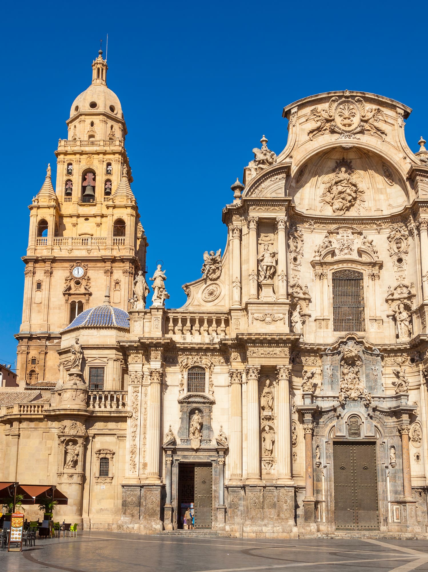 a large ornate building with a clock tower with Cathedral of Murcia in the background