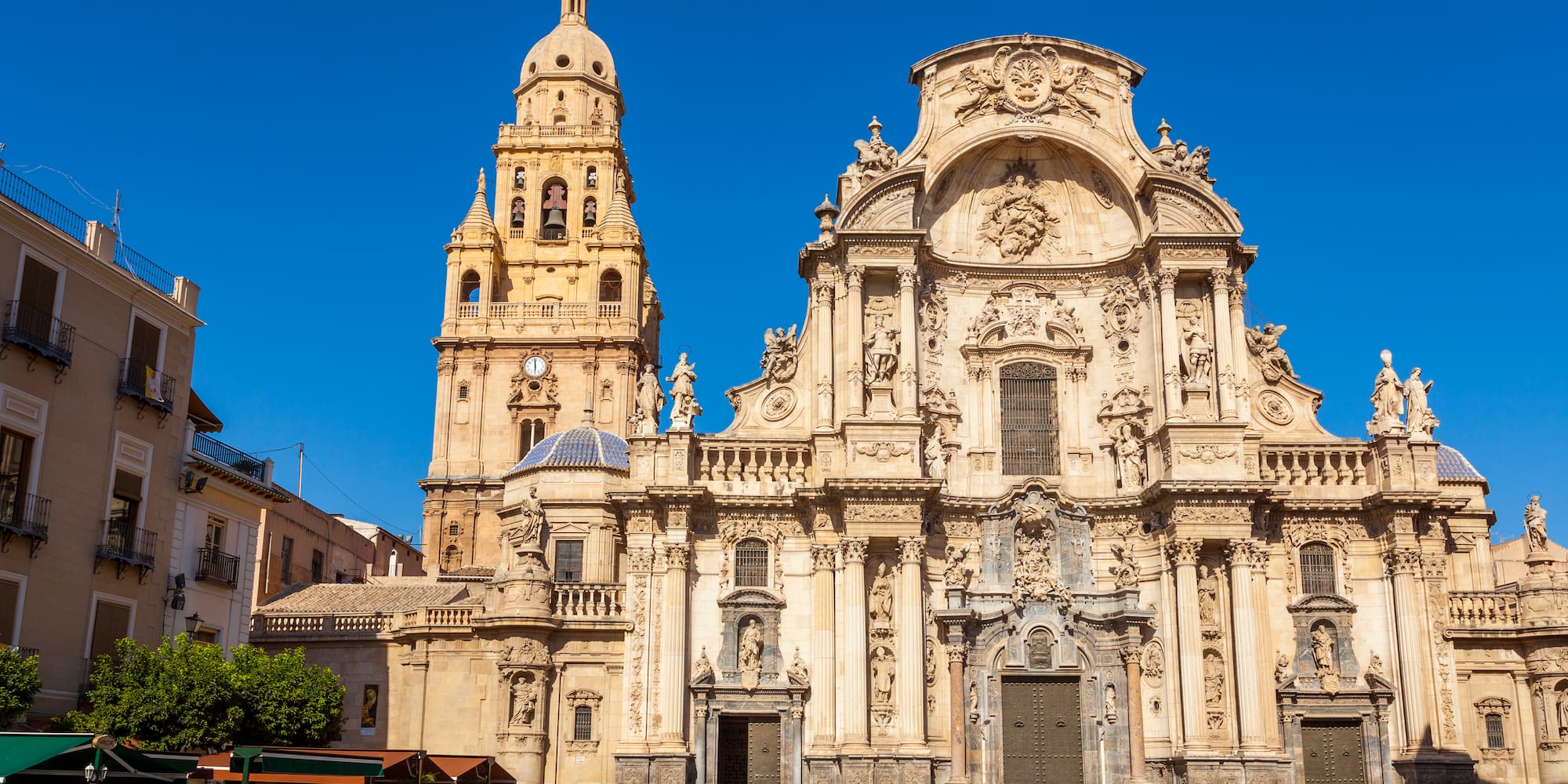 a large ornate building with a clock tower with Cathedral of Murcia in the background