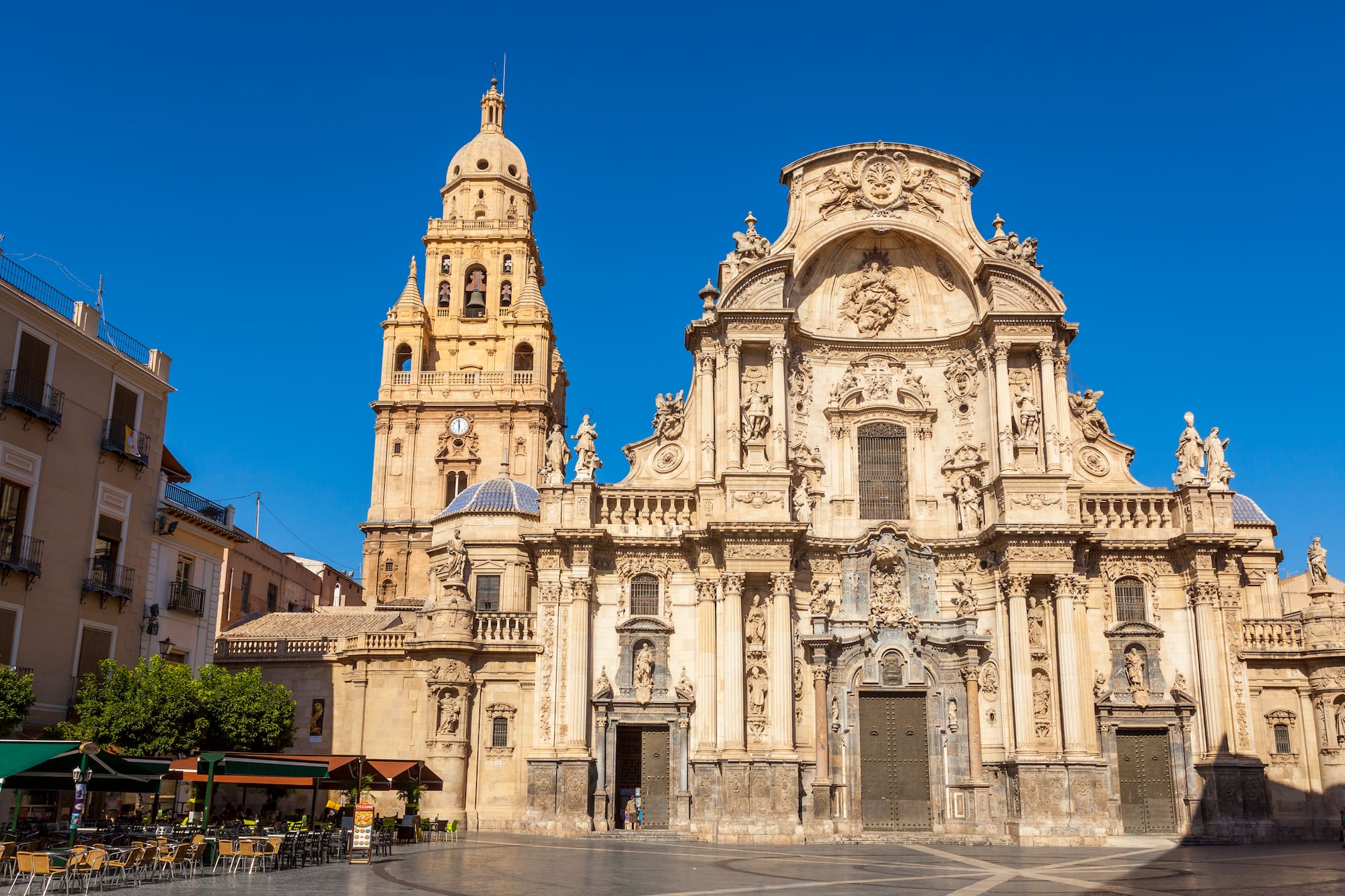 a large ornate building with a clock tower with Cathedral of Murcia in the background
