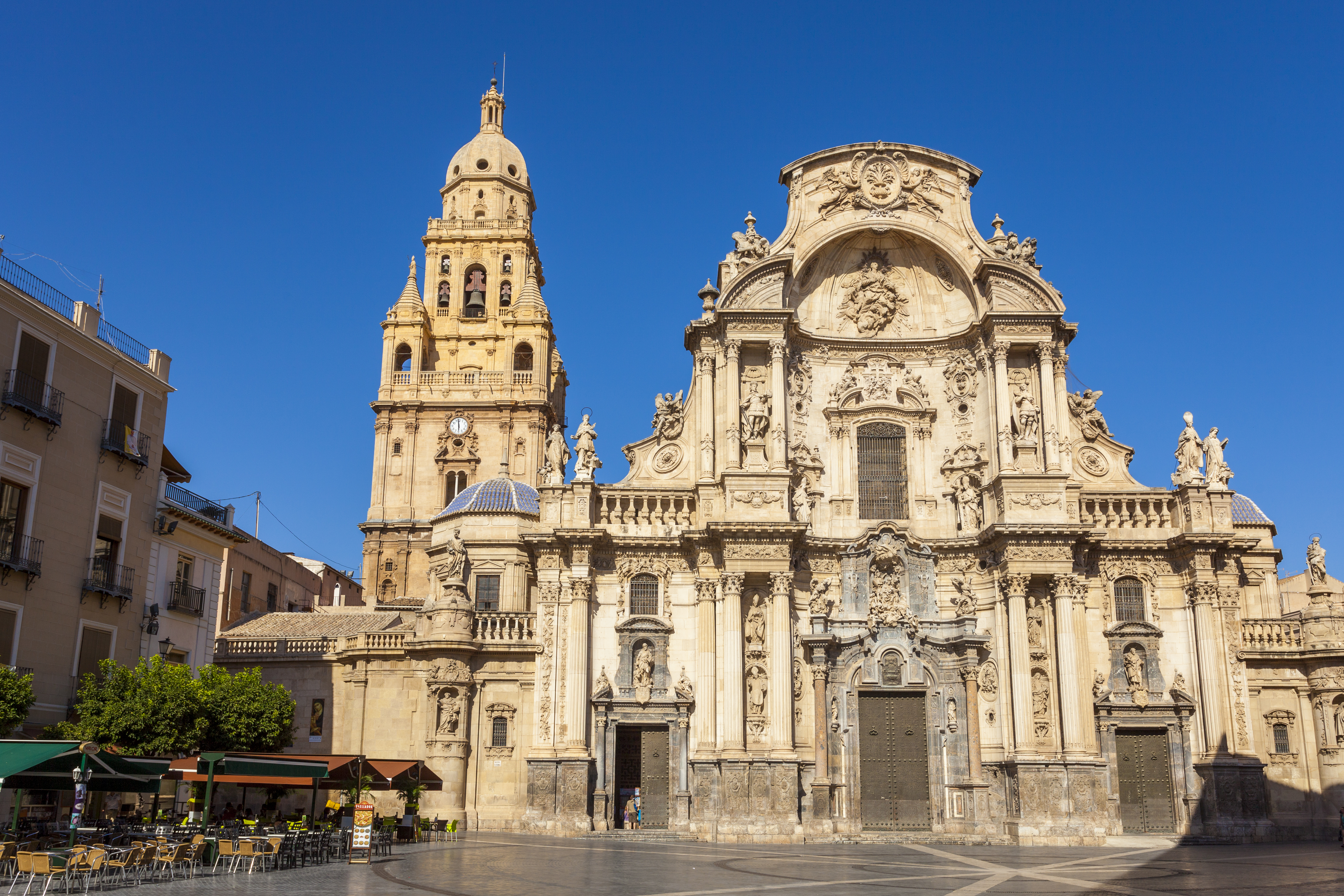 a large ornate building with a clock tower with Cathedral of Murcia in the background