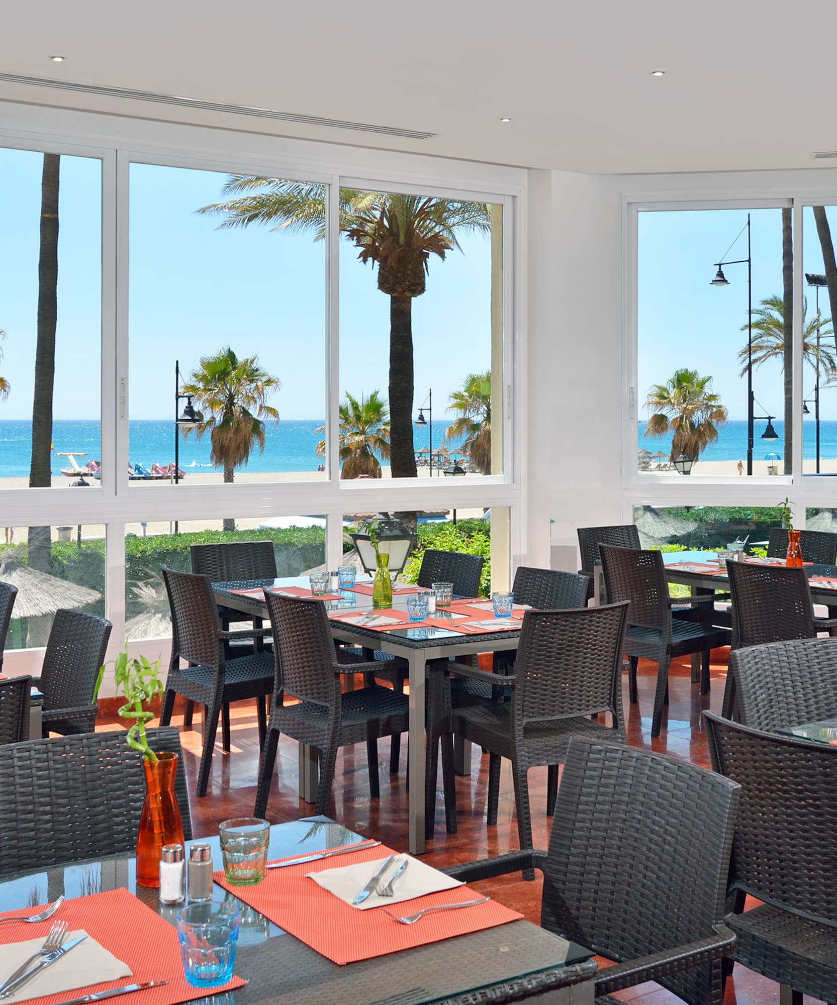 a room with tables and chairs and a view of the ocean