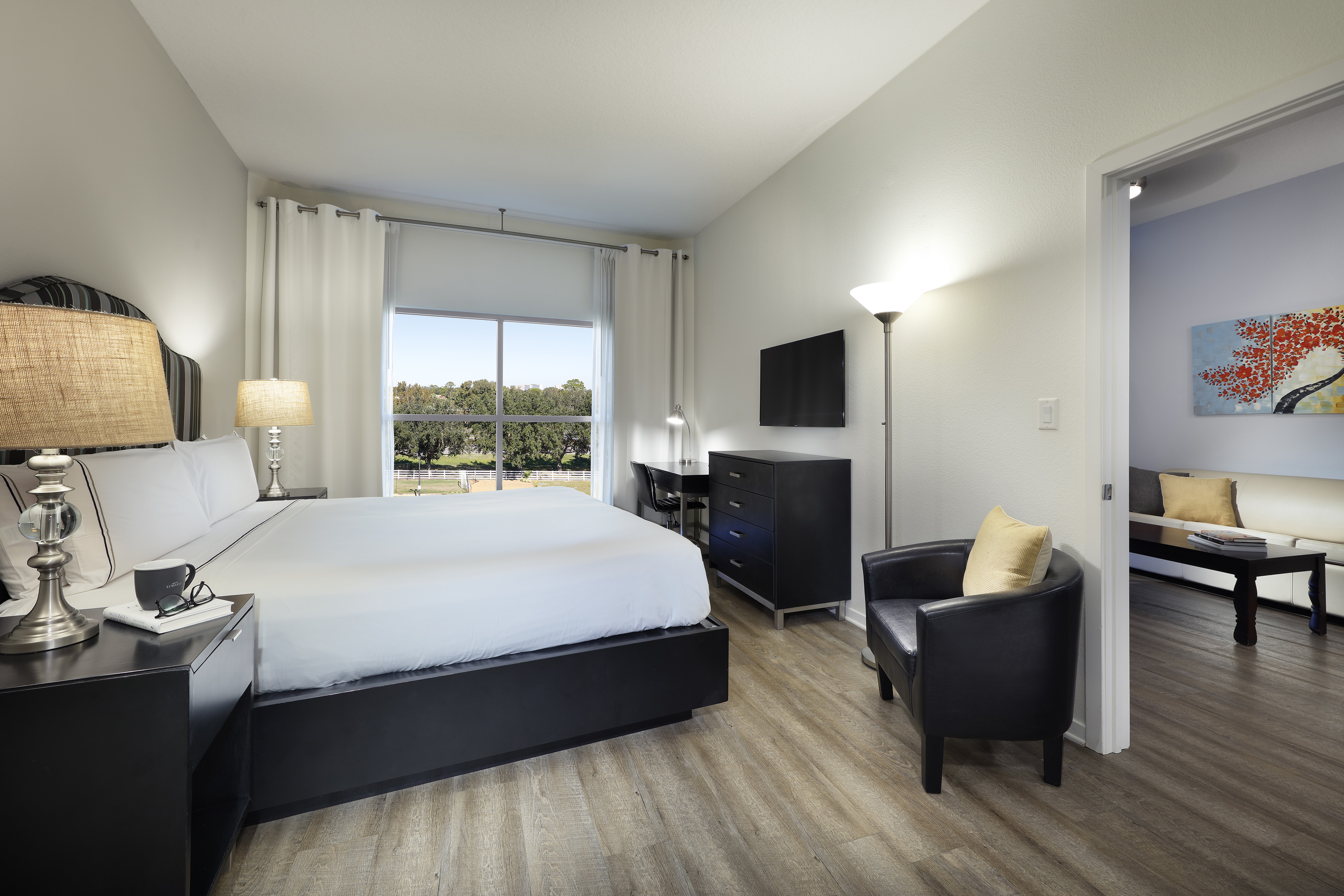 Modern hotel bedroom with king bed, desk, TV, armchair, and window view. - One-Bedroom Suite King-Size Bed - Meliá Orlando Celebration, Orlando
