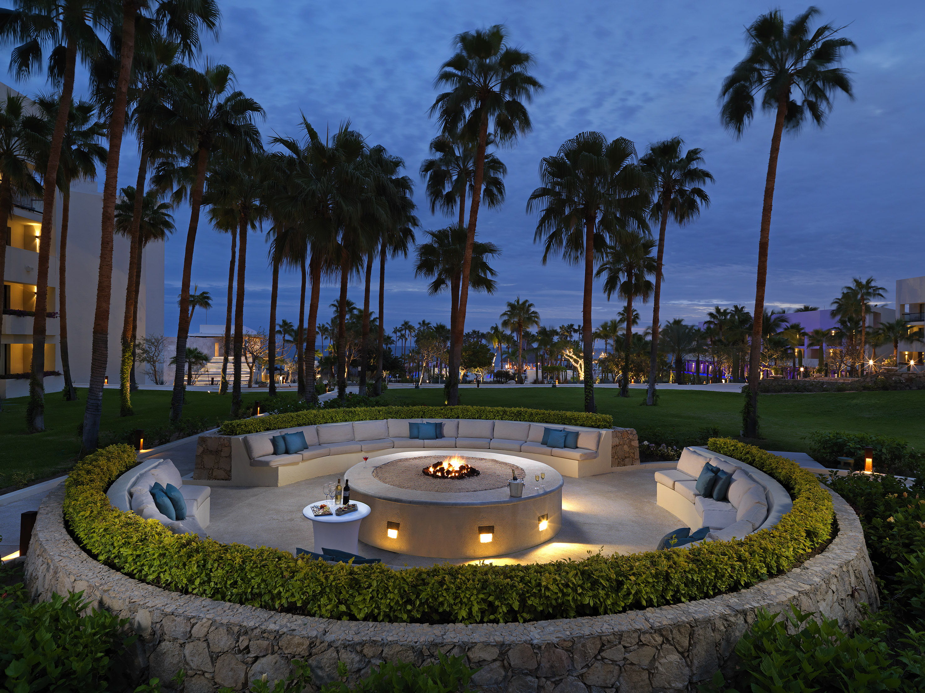 a circular fire pit with a fire pit surrounded by palm trees