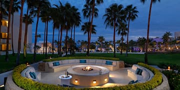 a circular fire pit with a fire pit surrounded by palm trees