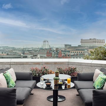a patio with a table and chairs and a city view