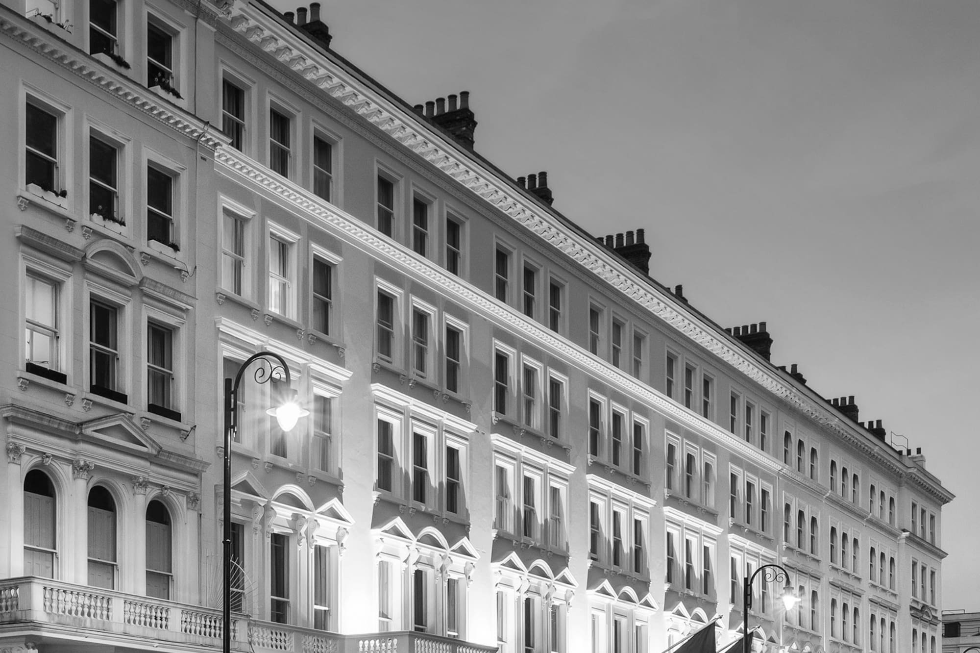Black and white long exposure of Melia Kensington hotel in London at night with car light trails.