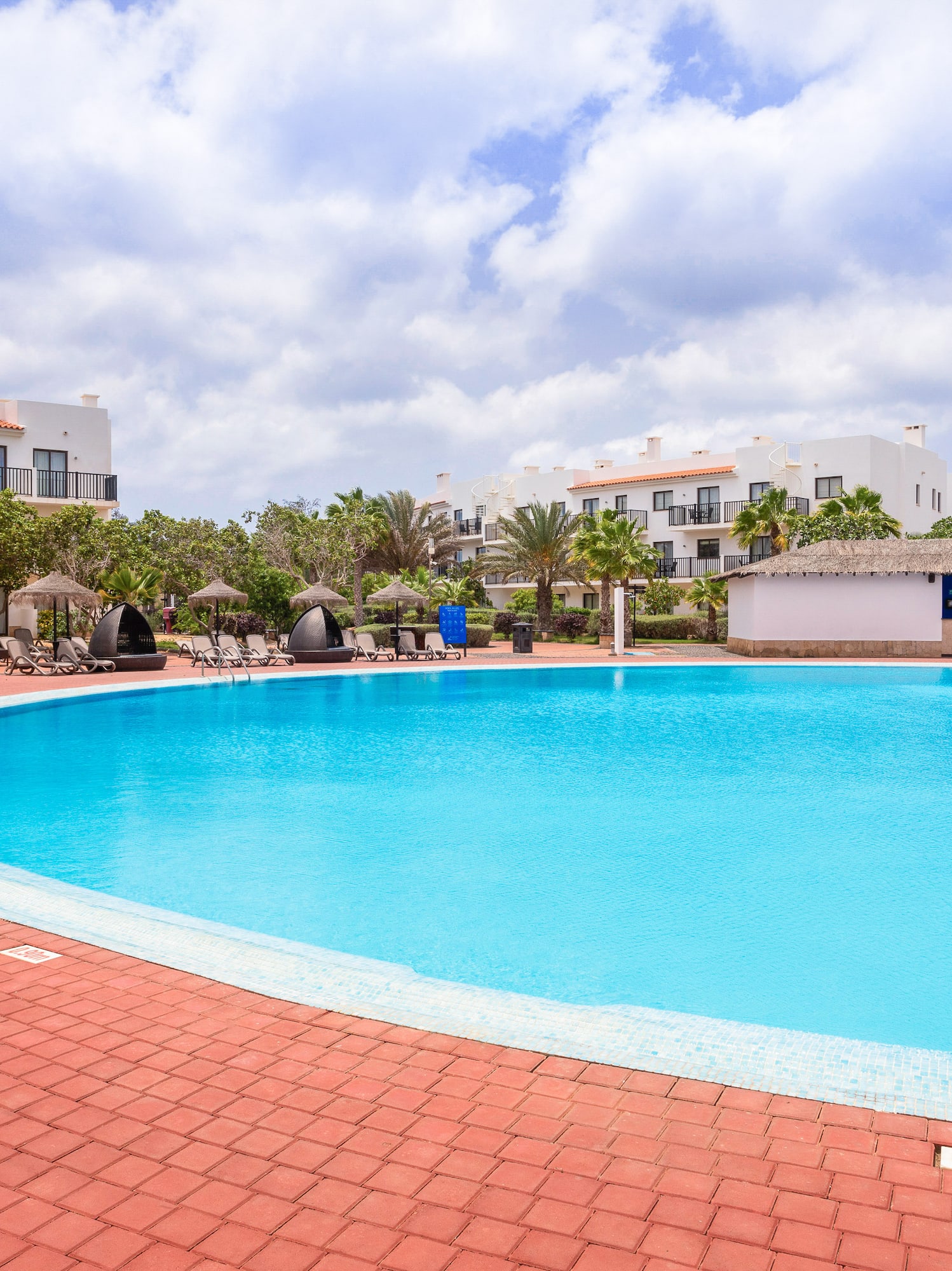 a pool with a brick walkway and trees