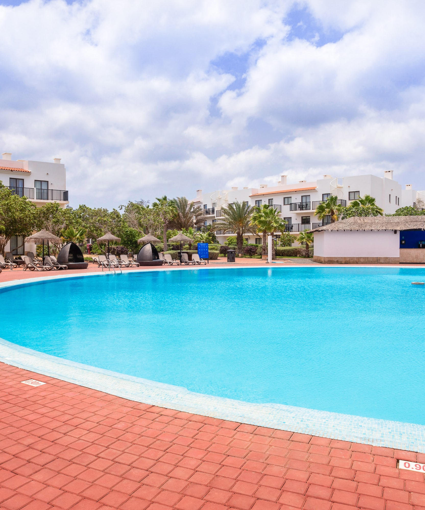 a pool with a brick walkway and trees