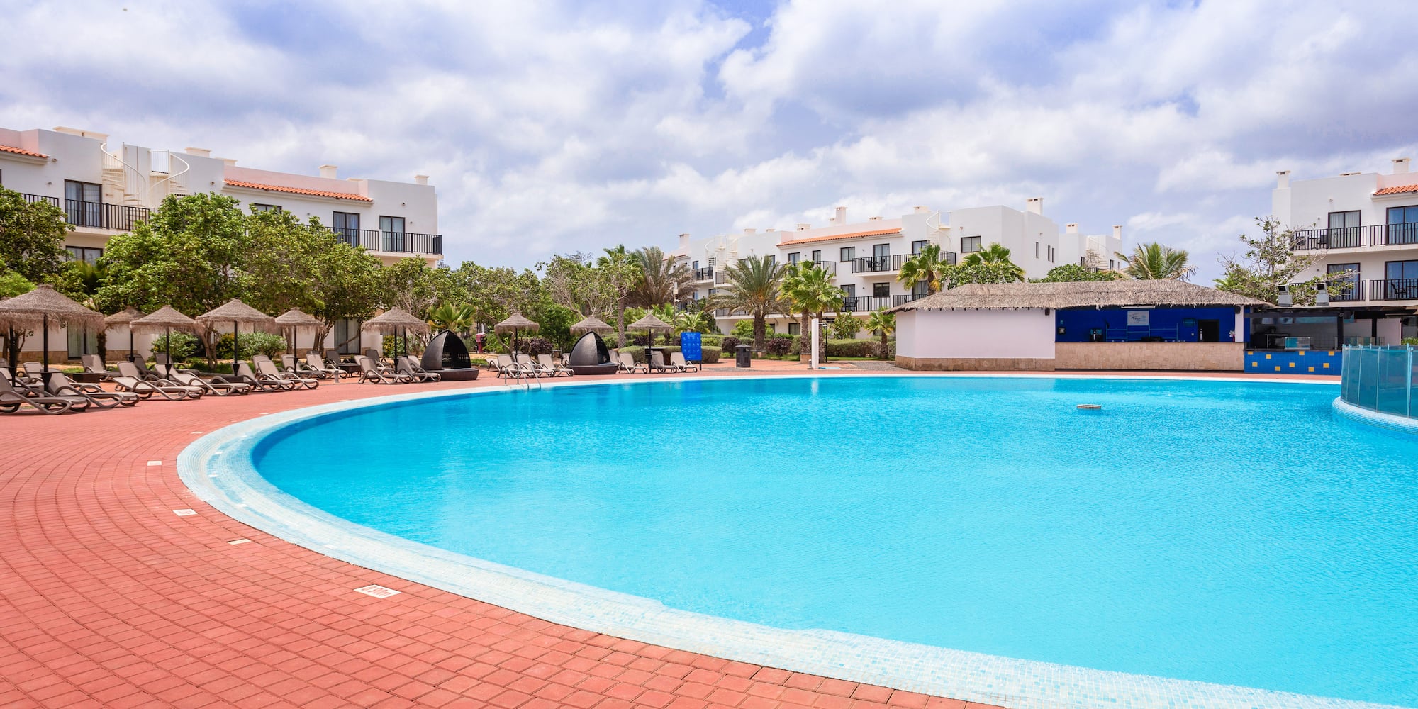 a pool with a brick walkway and trees