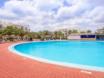 a pool with a brick walkway and trees