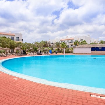 a pool with a brick walkway and trees