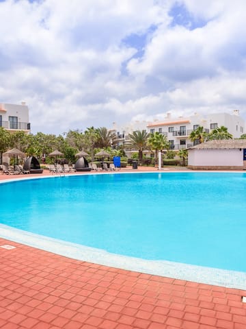 a pool with a brick walkway and trees