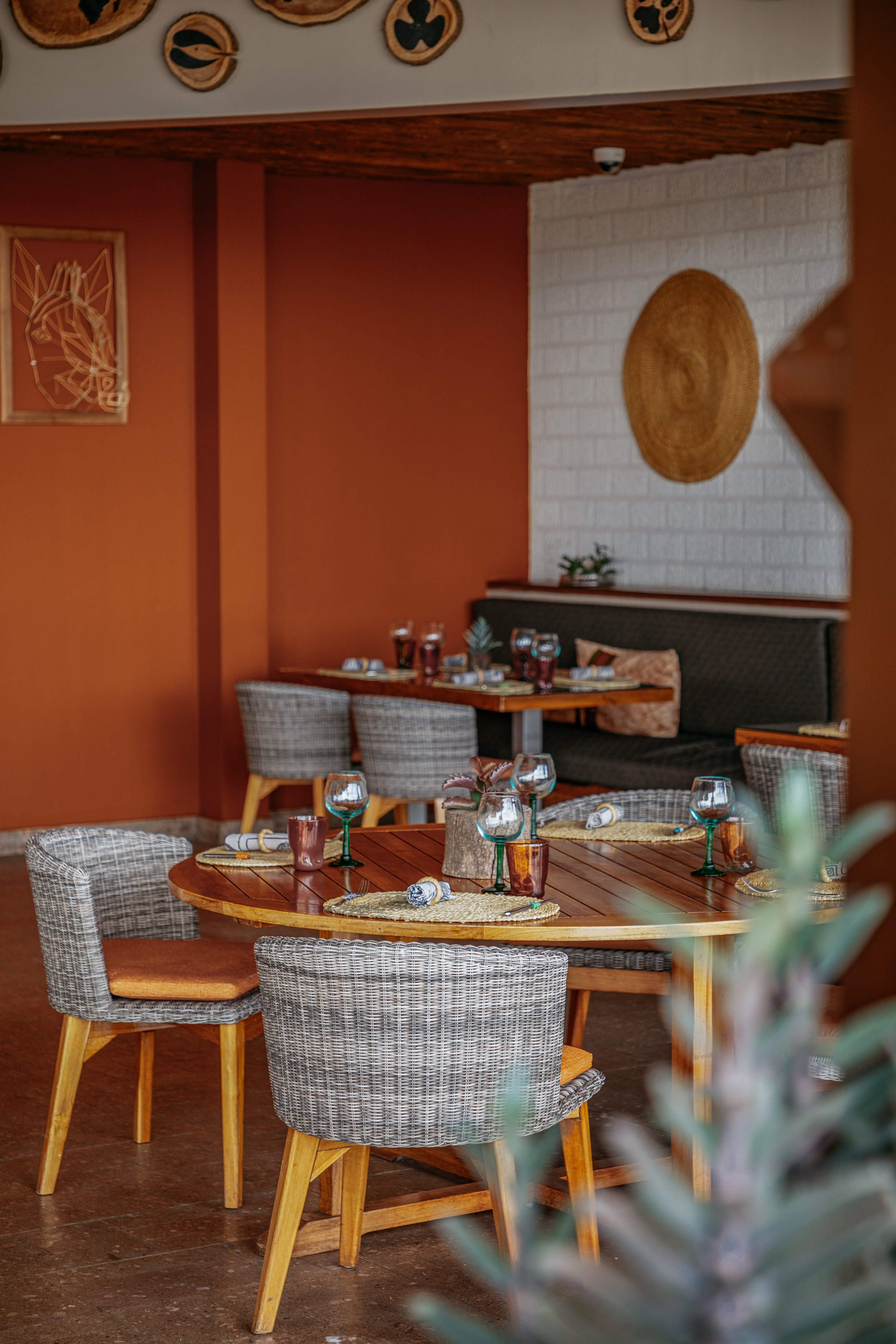 Restaurant dining tables set with wicker chairs and terracotta walls.