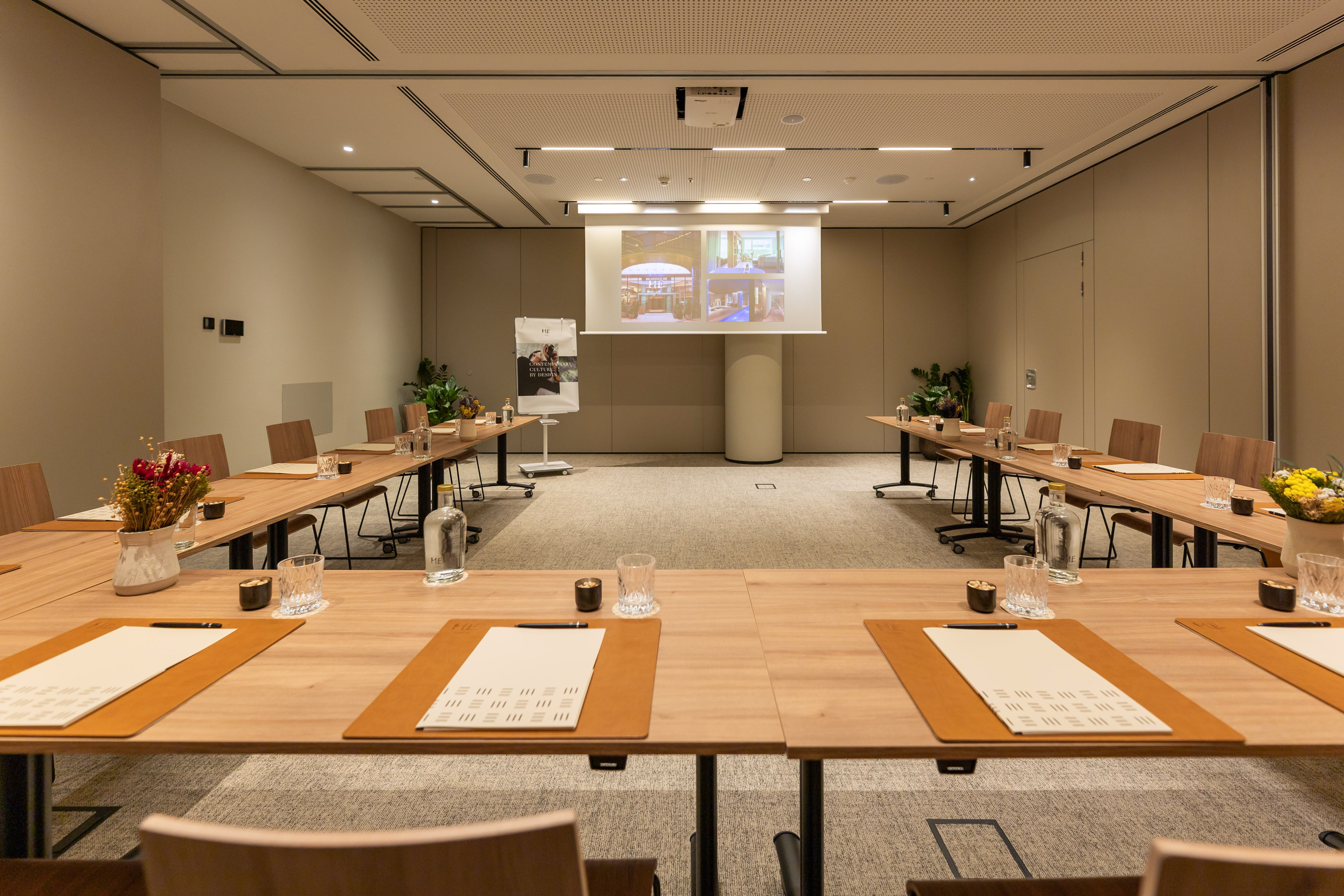 Modern conference room with U-shaped tables, projector, and professional setup.