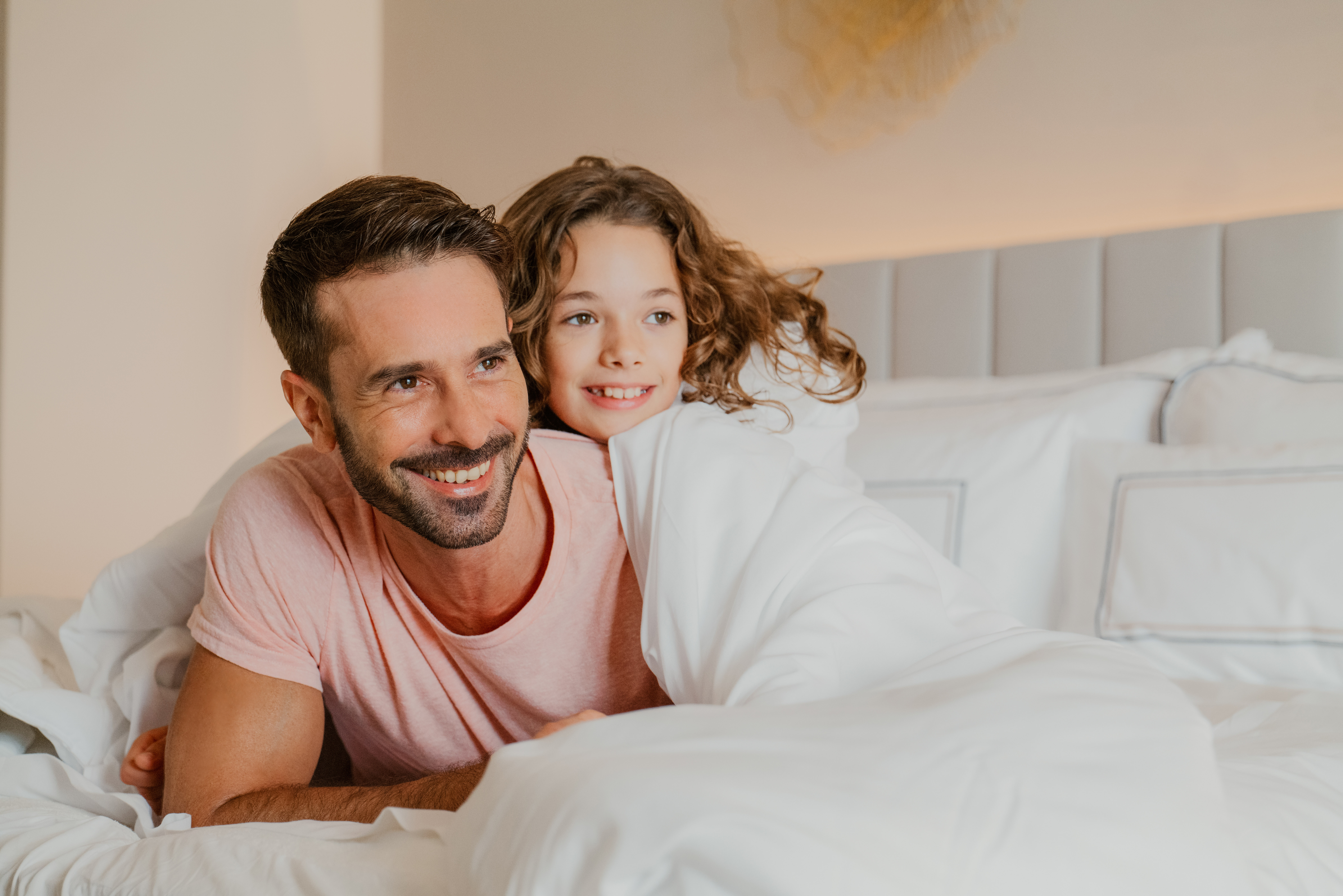 Smiling father and daughter snuggled together in a cozy bed.
