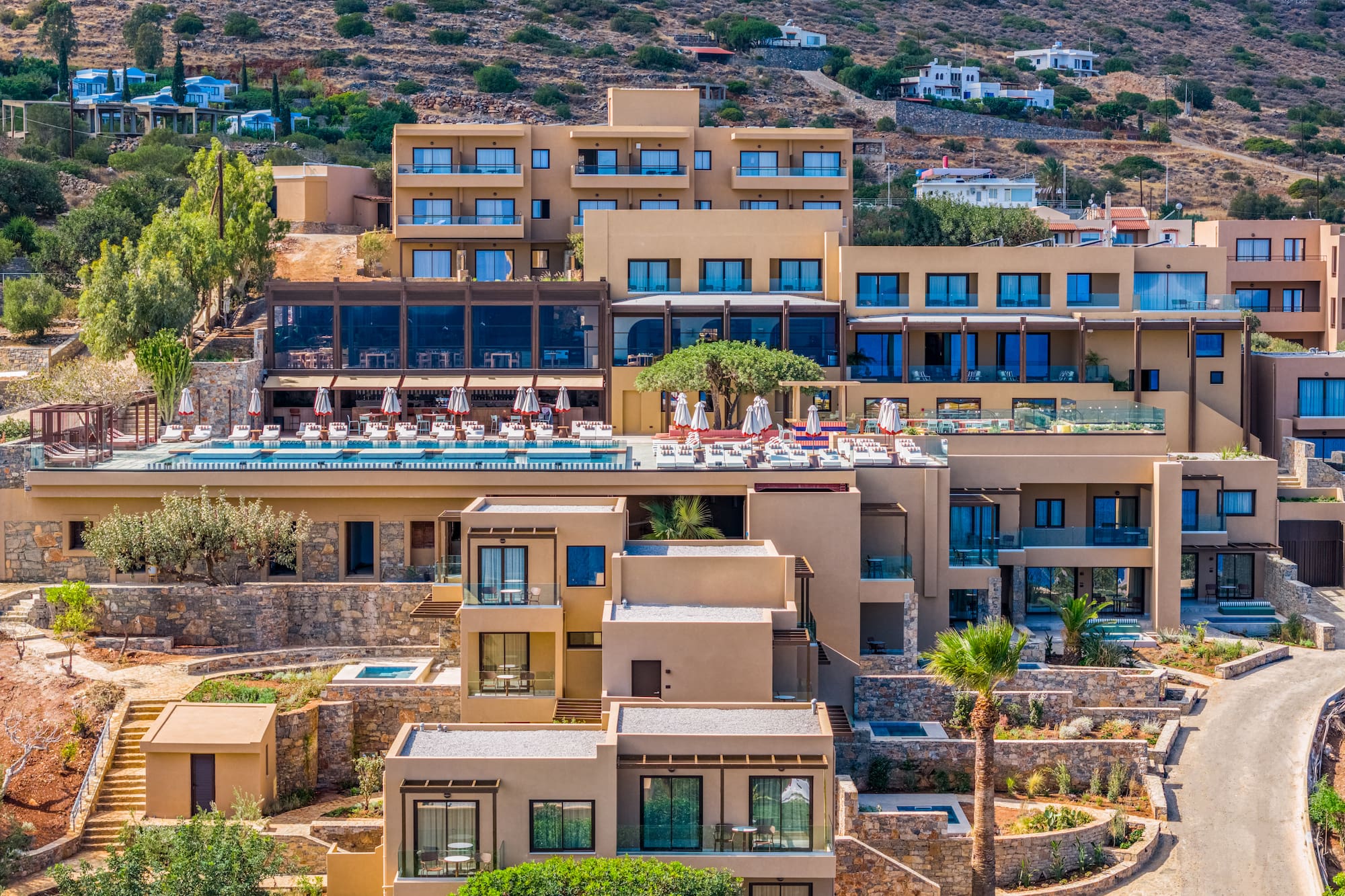 Luxury terraced resort on hillside with large swimming pool and balconies.