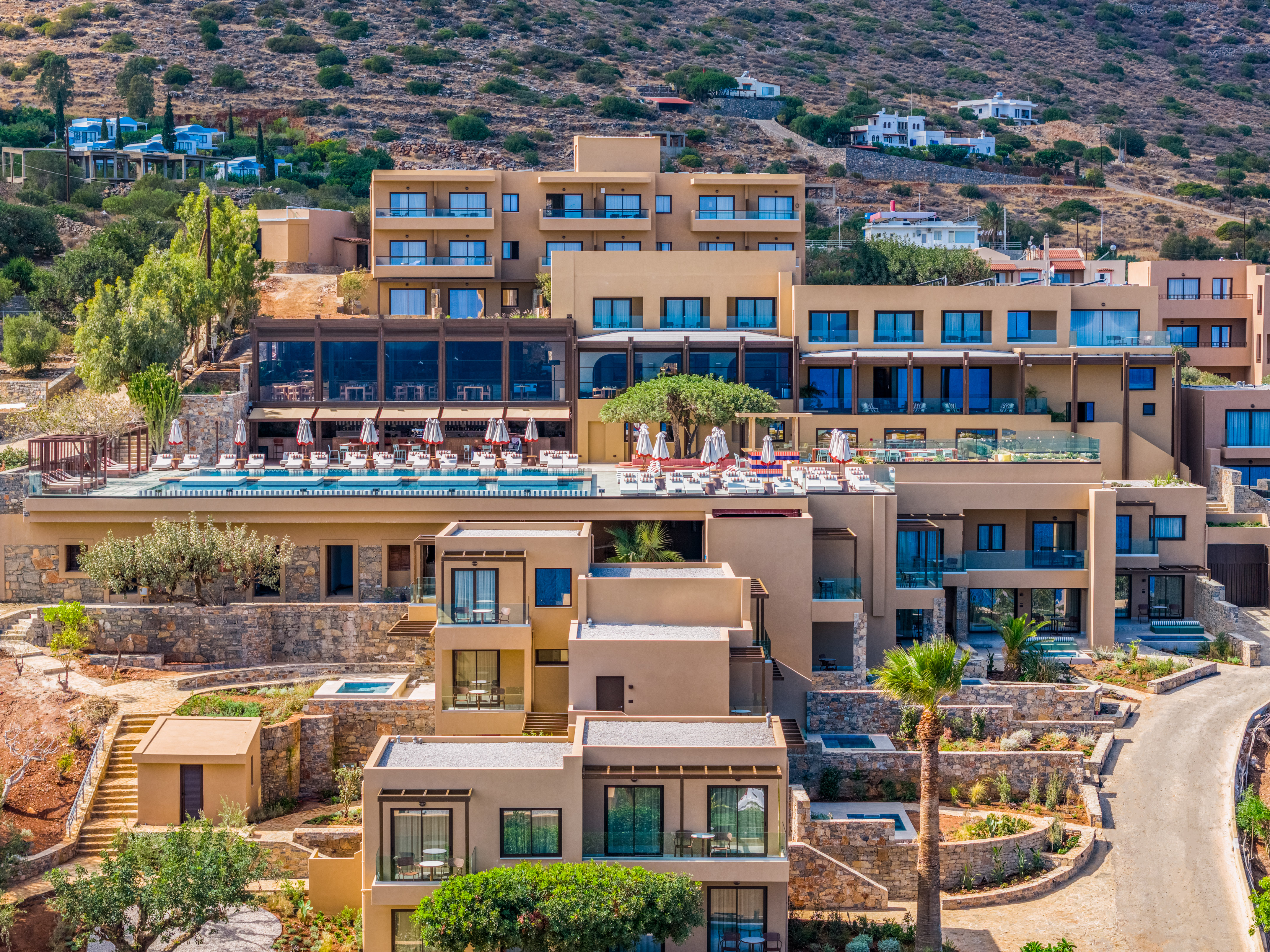 Luxury terraced resort on hillside with large swimming pool and balconies.
