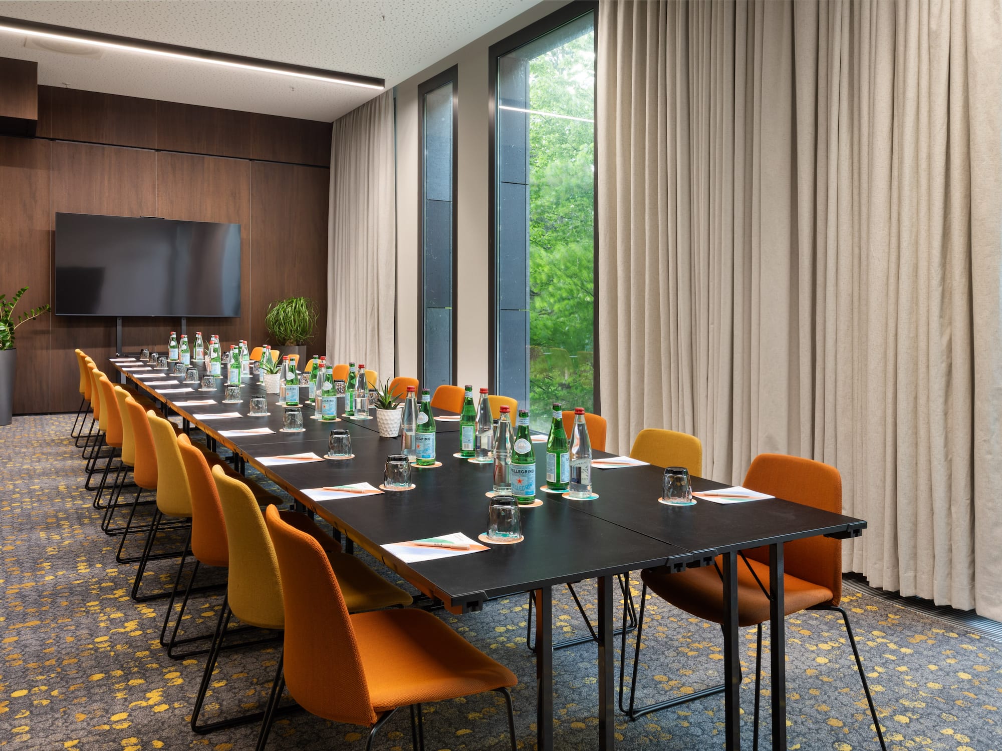 a long conference table with bottles of water and chairs