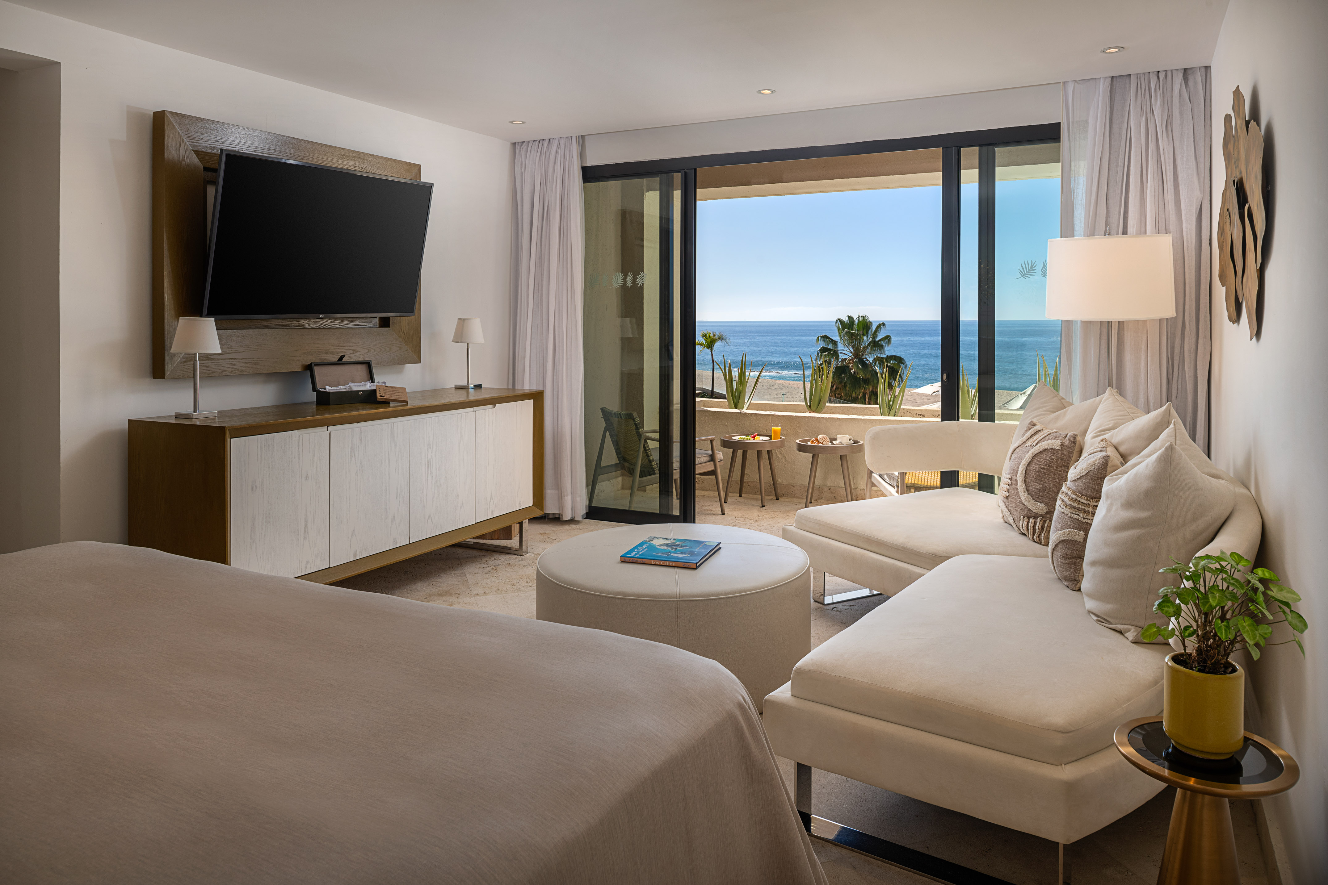 Ocean view hotel suite with balcony, modern design, and lounge.