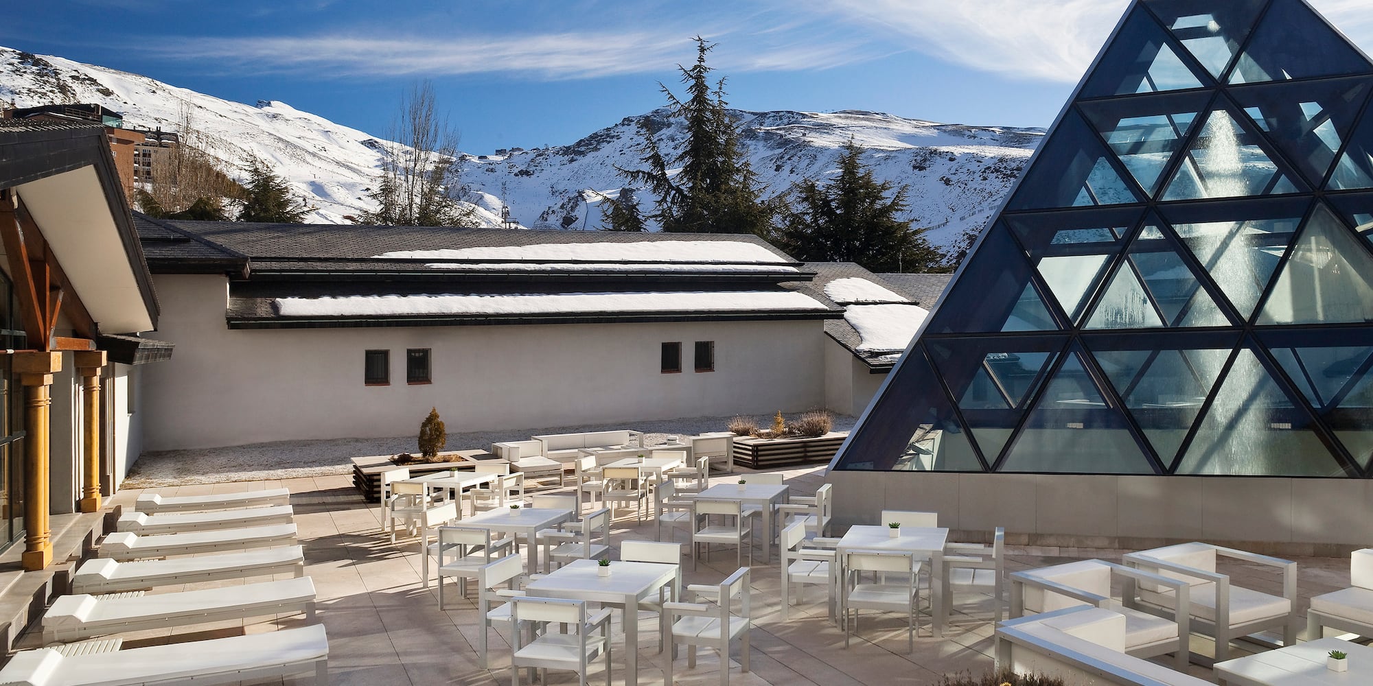 a building with a pyramid shaped glass roof and tables and chairs