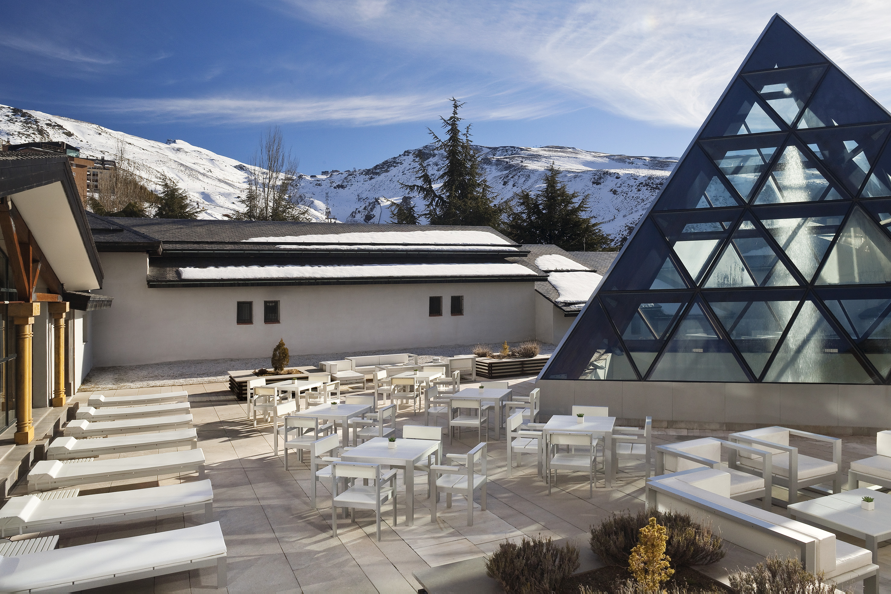 a building with a pyramid shaped glass roof and tables and chairs