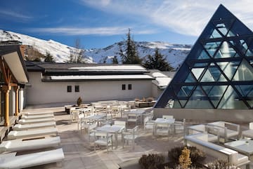 a building with a pyramid shaped glass roof and tables and chairs
