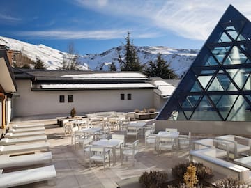 a building with a pyramid shaped glass roof and tables and chairs