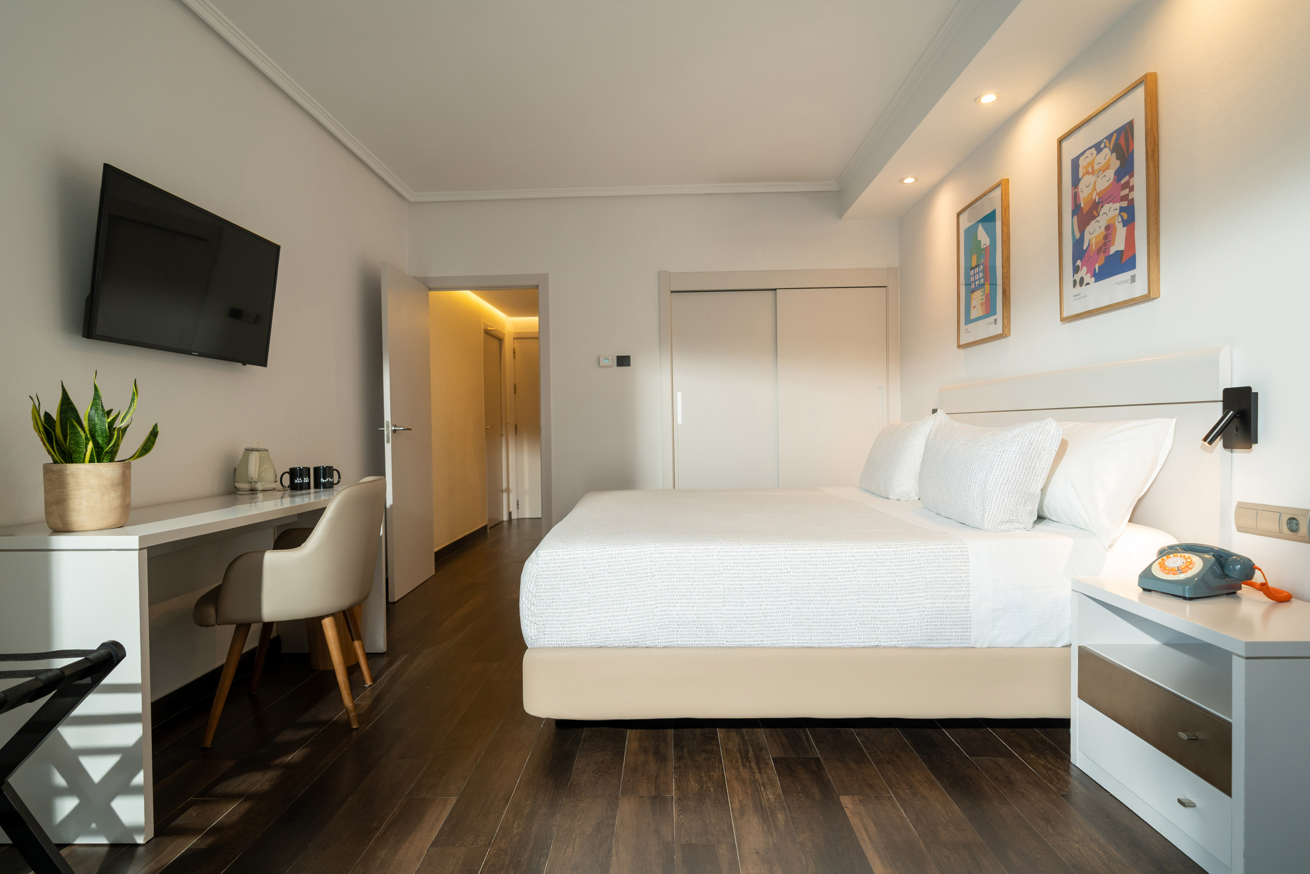 Bright hotel room with large bed, modern decor, workspace, and wooden floor.