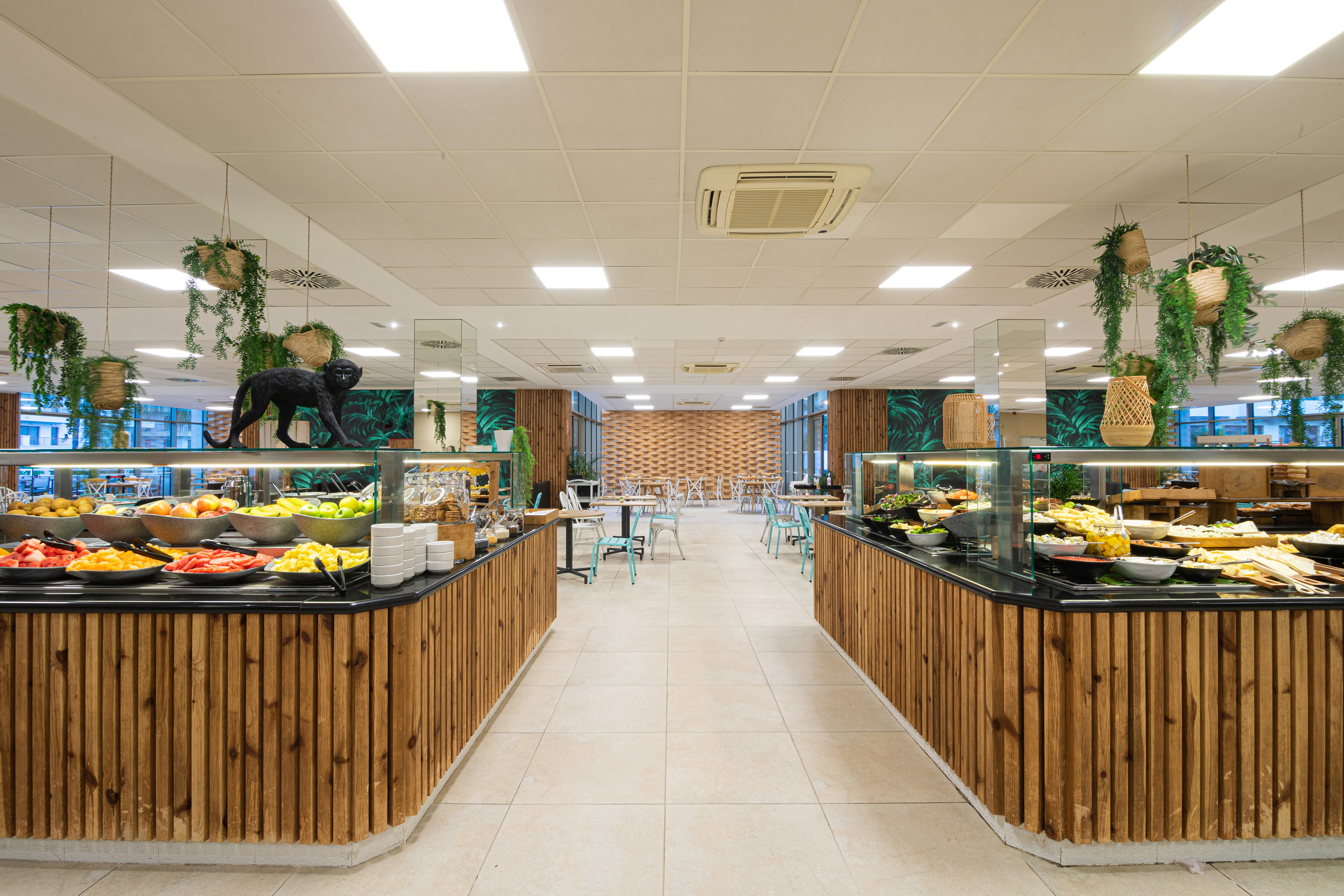 Tropical buffet restaurant with fresh fruits, salads, and monkey statue.