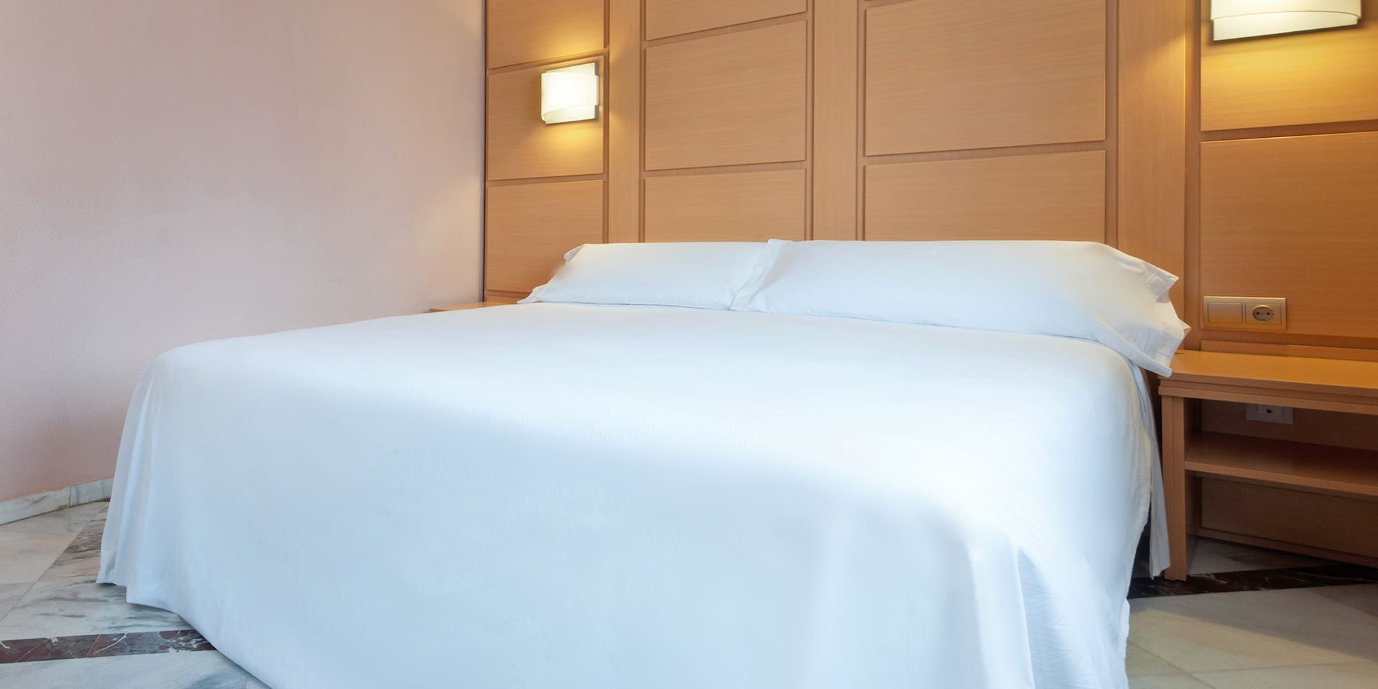 a bed with a white sheet and pillows