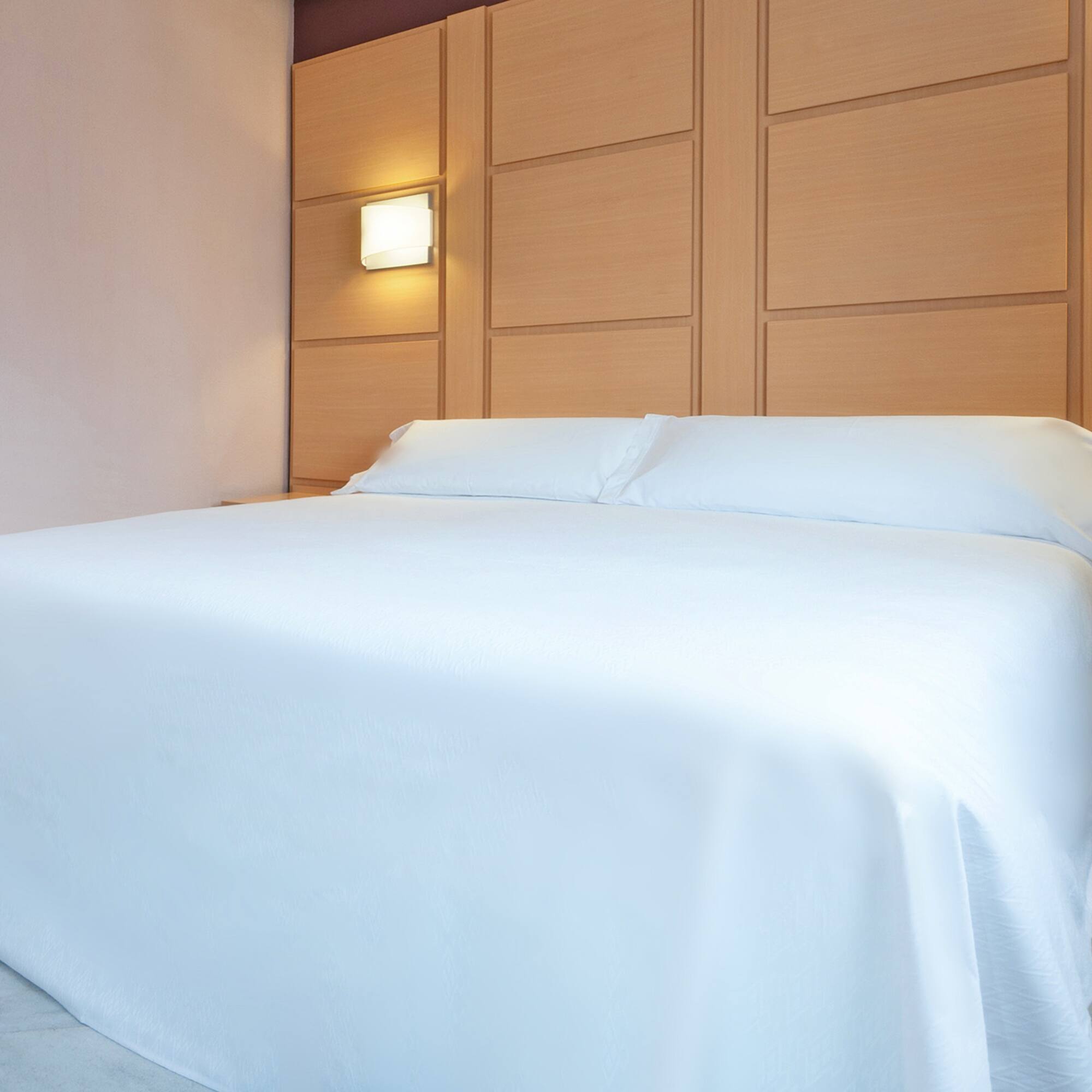 a bed with a white sheet and pillows