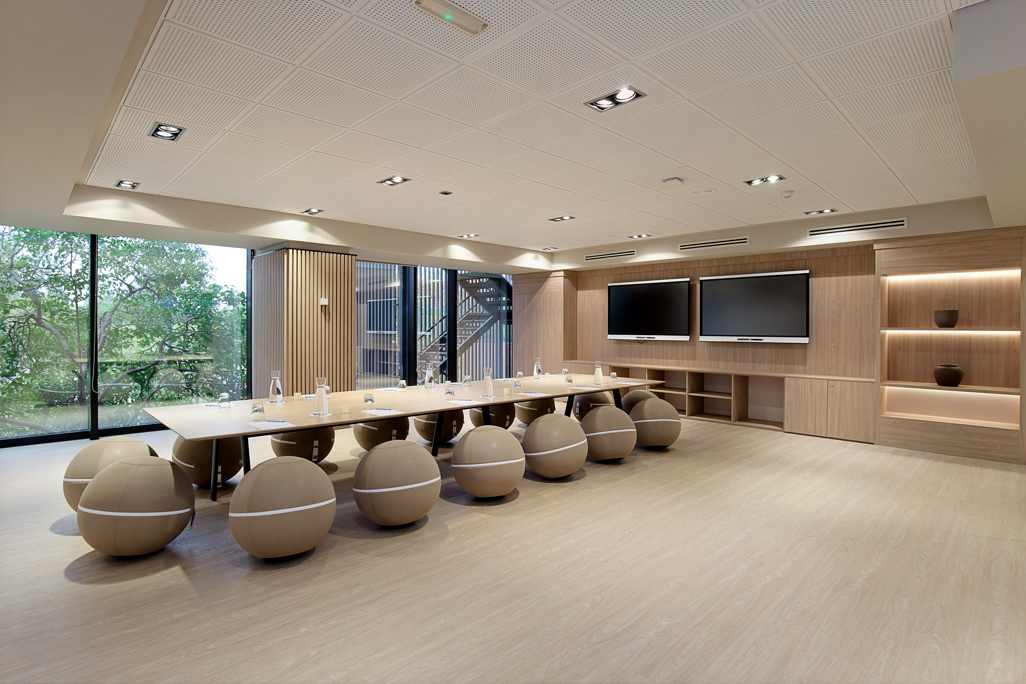 Modern meeting room with unique spherical seating, dual displays, and natural light.