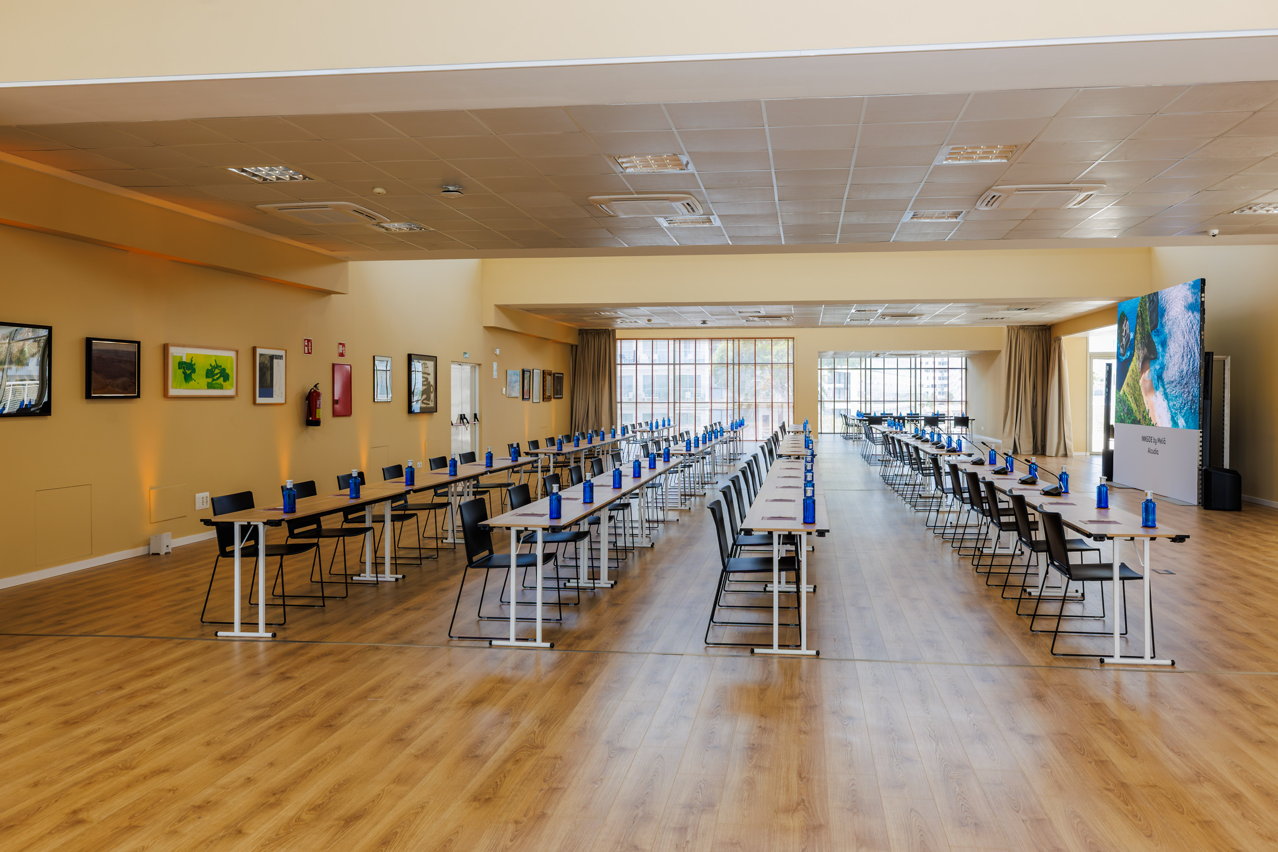 Bright, modern conference room with tables, chairs, and large screen for events.