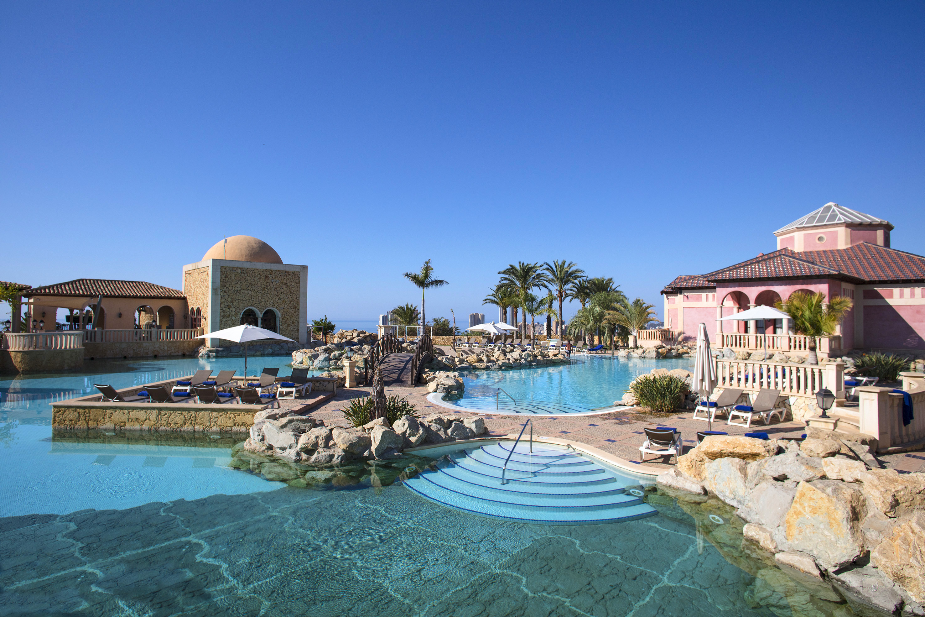 a pool with a stone building and a dome roof