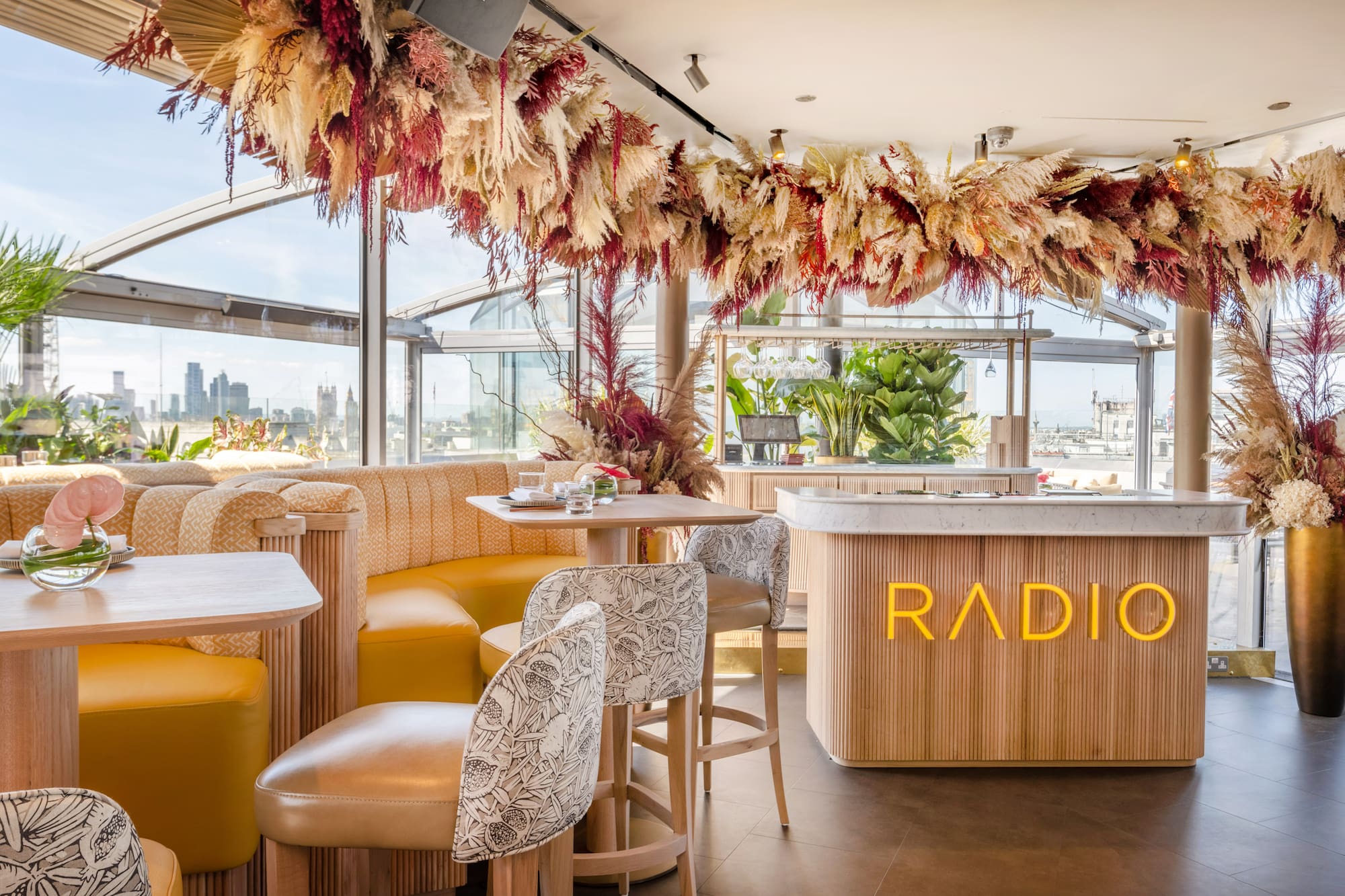 A room furnished with tables and chairs, featuring a bar beside a spacious window.
