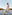 a woman in a skirt and top standing on a railing by water