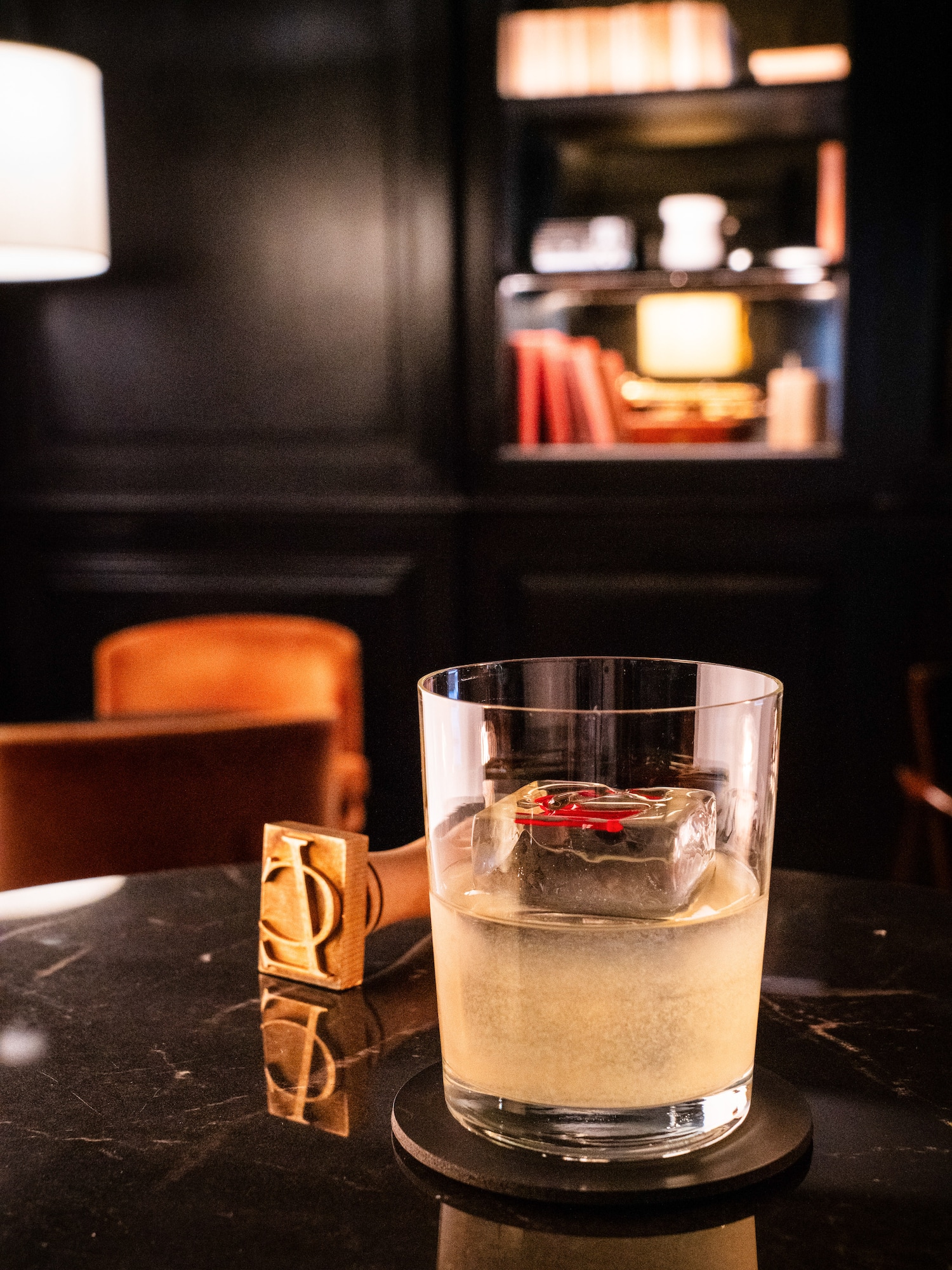a glass of liquid with ice on a table