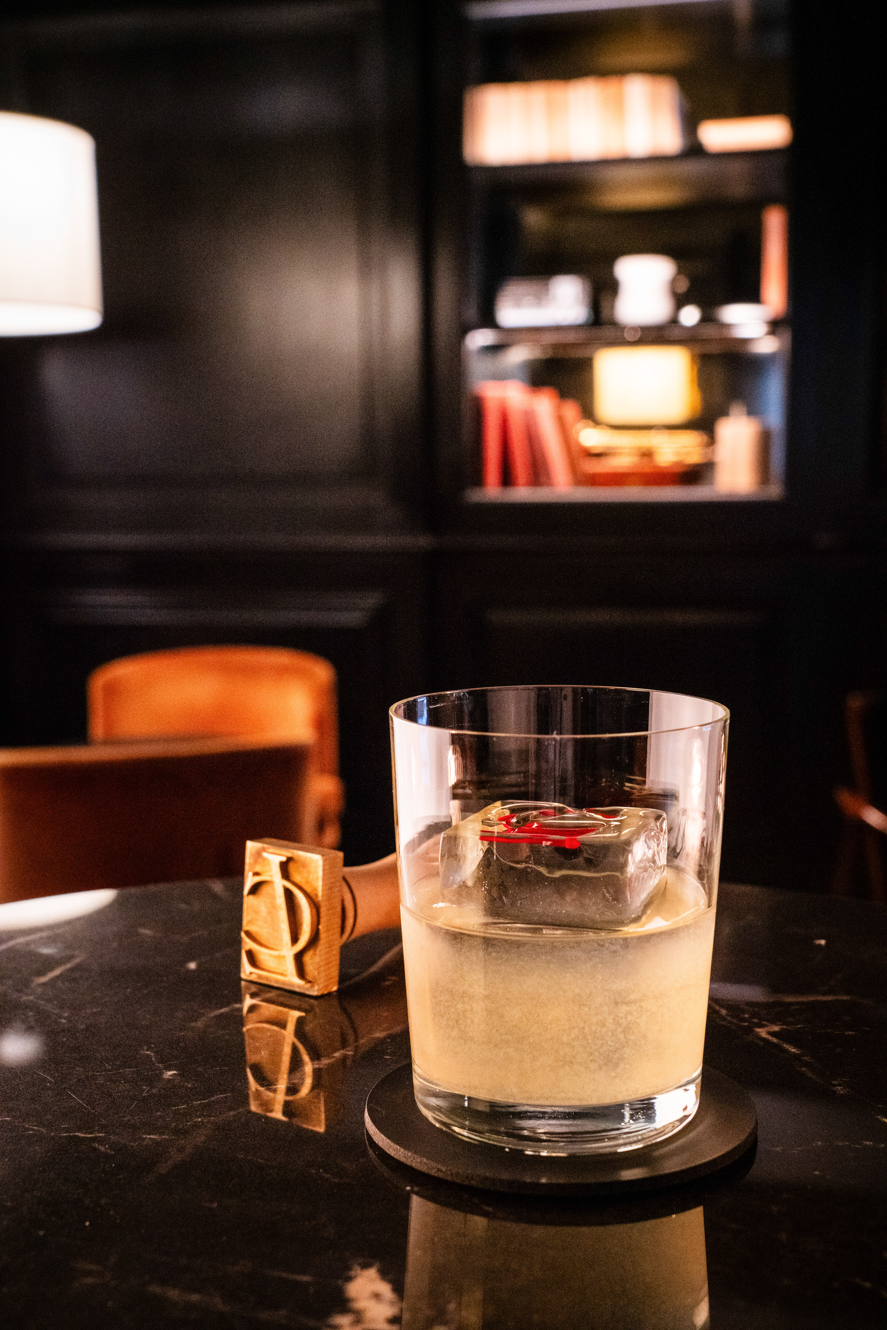a glass of liquid with ice on a table