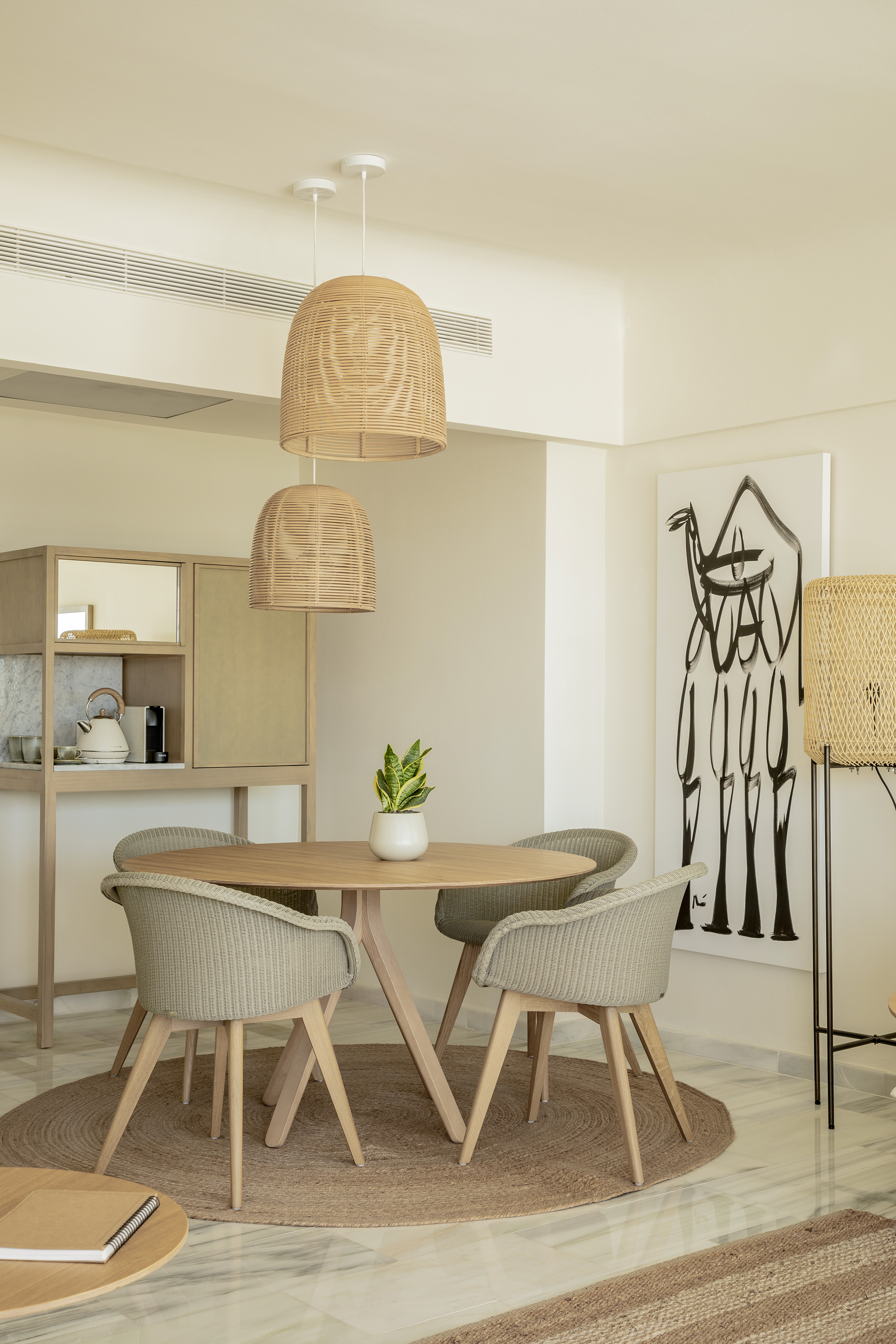 Modern dining area: round wood table, wicker chairs, rattan pendant lights.